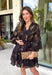 Step into the season with effortless style in this beautifully detailed dress from Entro. Designed with a classic black backdrop and a rich floral print in shades of brown and tan, this timeless dress captures the warmth of fall with every detail. The flattering v-neckline and button-front design create a polished silhouette, while the included matching belt defines the waist for a customizable fit. Finished with ¾ balloon sleeves, a playful ruffle hem, convenient side pockets.