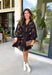 Step into the season with effortless style in this beautifully detailed dress from Entro. Designed with a classic black backdrop and a rich floral print in shades of brown and tan, this timeless dress captures the warmth of fall with every detail. The flattering v-neckline and button-front design create a polished silhouette, while the included matching belt defines the waist for a customizable fit. Finished with ¾ balloon sleeves, a playful ruffle hem, convenient side pockets.