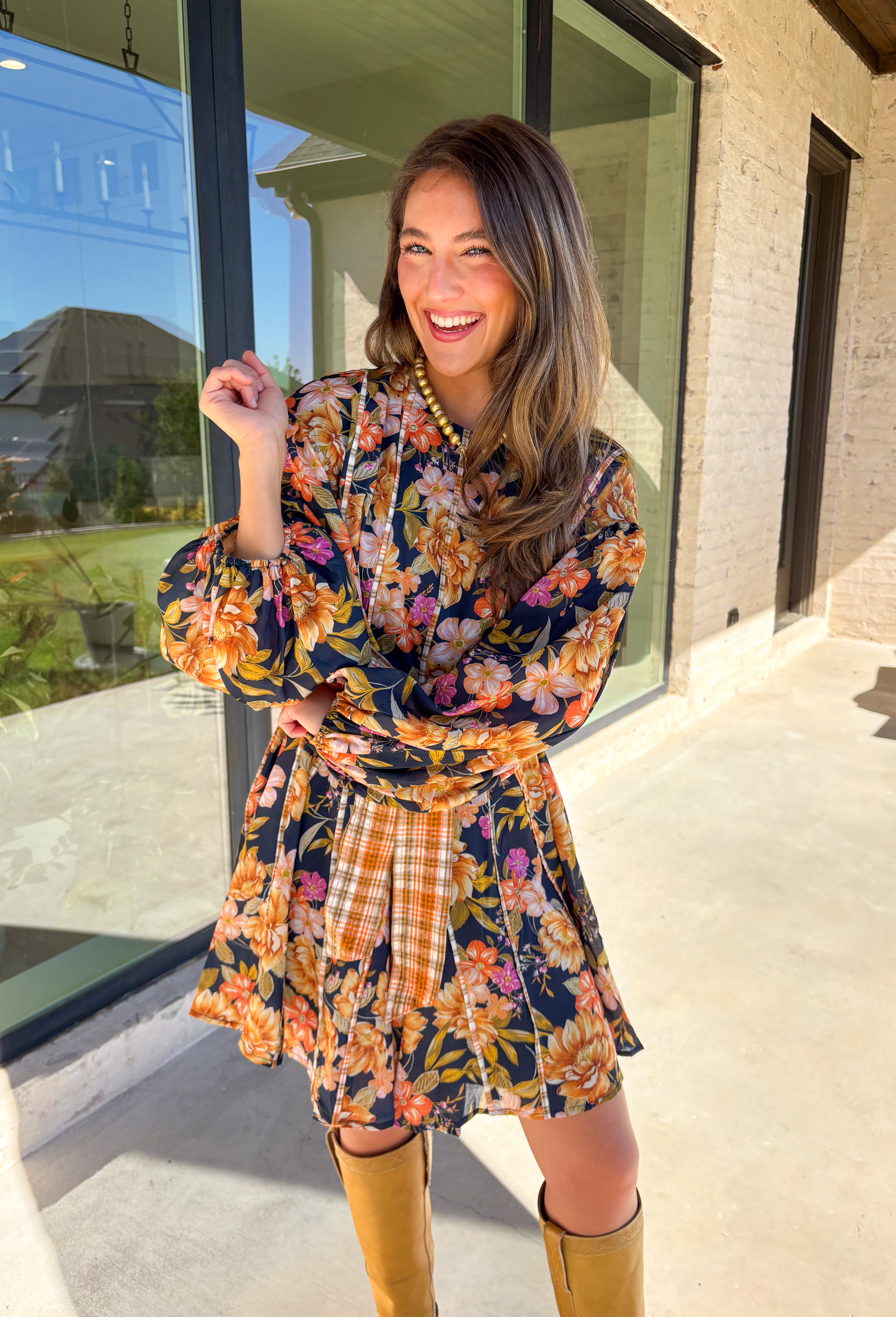 Bring bold fall energy to your wardrobe with this navy long sleeve dress featuring a colorful floral print in rich autumn shades. A playful orange plaid self-tie belt cinches the waist for a flattering finish, while striped piping throughout ties the look together with unique detail. The elastic cuff sleeves keep the fit comfortable, and the lightweight fabric makes it easy to wear through the season. Effortlessly fun and polished, this dress is a perfect choice for fall outings and gatherings.