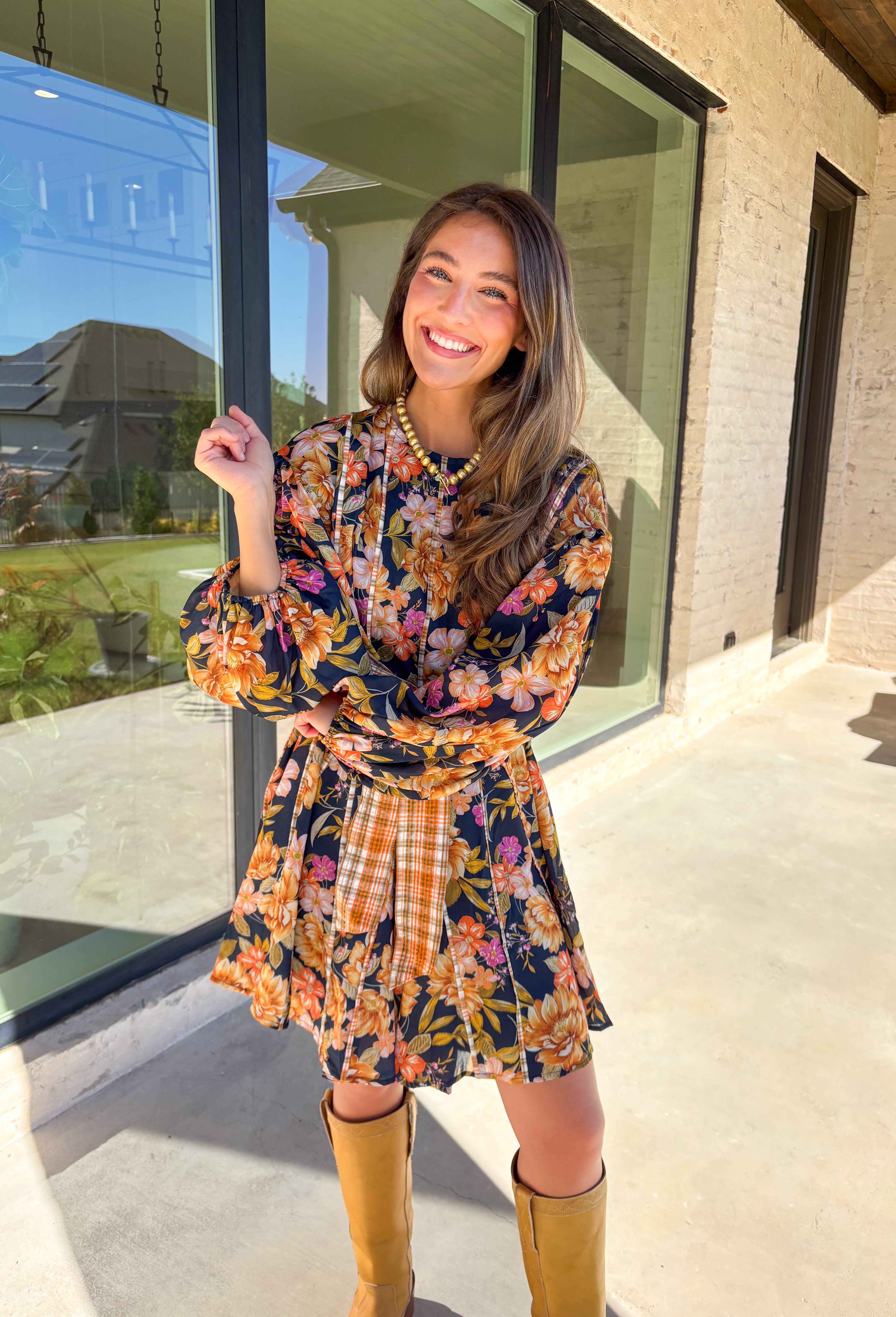 Bring bold fall energy to your wardrobe with this navy long sleeve dress featuring a colorful floral print in rich autumn shades. A playful orange plaid self-tie belt cinches the waist for a flattering finish, while striped piping throughout ties the look together with unique detail. The elastic cuff sleeves keep the fit comfortable, and the lightweight fabric makes it easy to wear through the season. Effortlessly fun and polished, this dress is a perfect choice for fall outings and gatherings.
