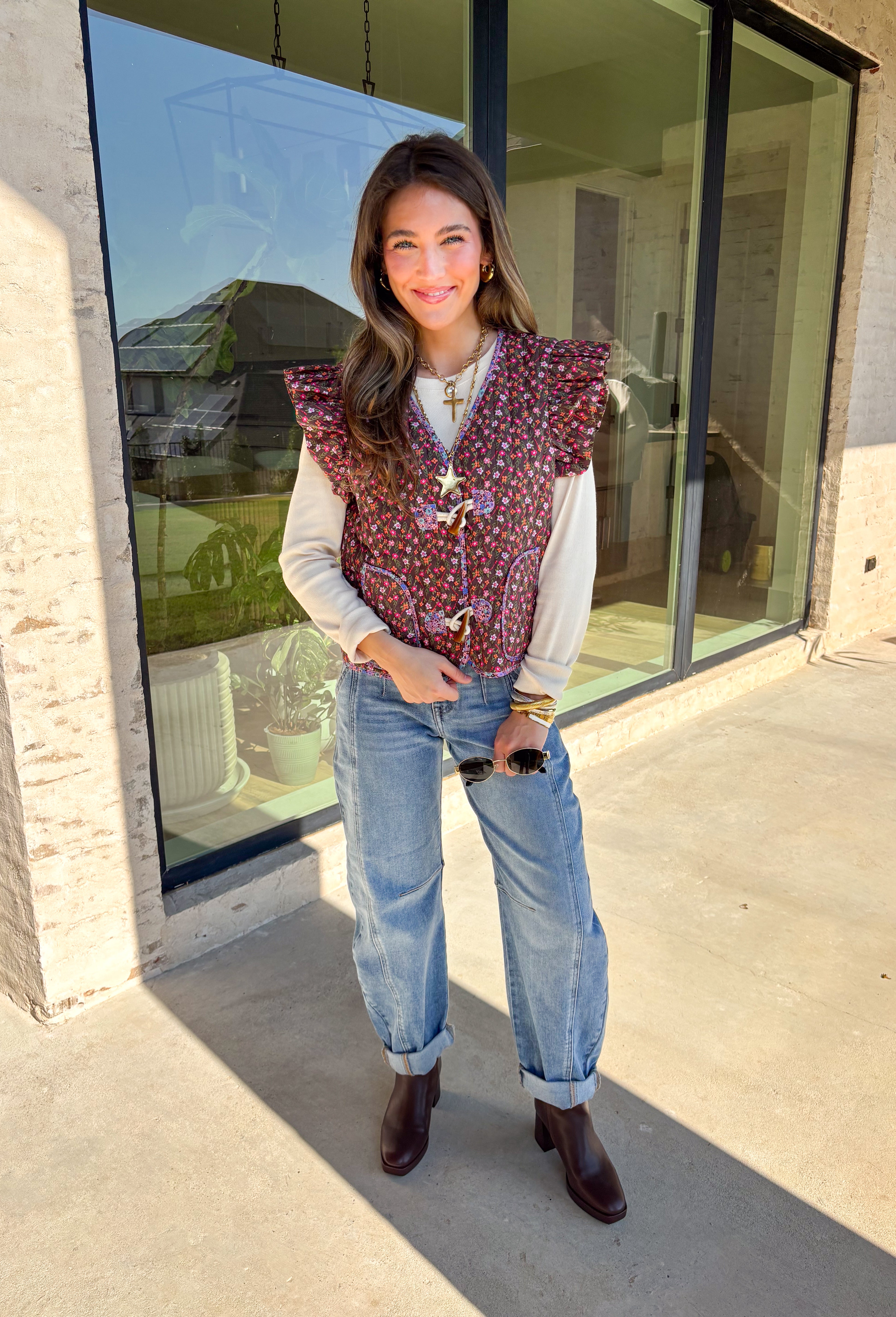 This charming quilted vest is giving all the cozy fall vibes with a pop of cheerful color. The brown base is covered in a dainty floral print in soft shades of pink, orange, and green—perfect for layering over your favorite long sleeve tops. Ruffle sleeves and oversized button closures add just the right amount of whimsy!