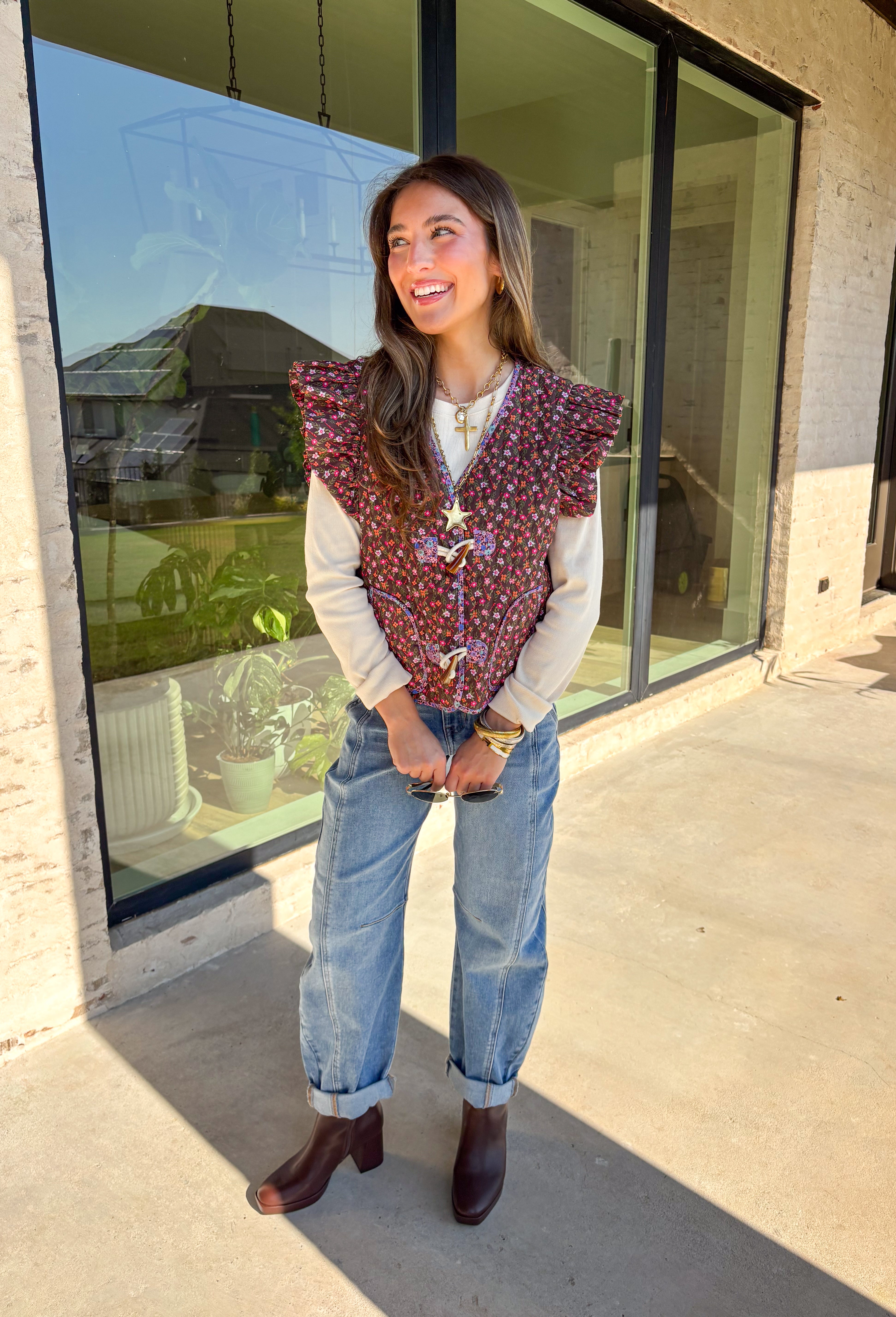 This charming quilted vest is giving all the cozy fall vibes with a pop of cheerful color. The brown base is covered in a dainty floral print in soft shades of pink, orange, and green—perfect for layering over your favorite long sleeve tops. Ruffle sleeves and oversized button closures add just the right amount of whimsy!