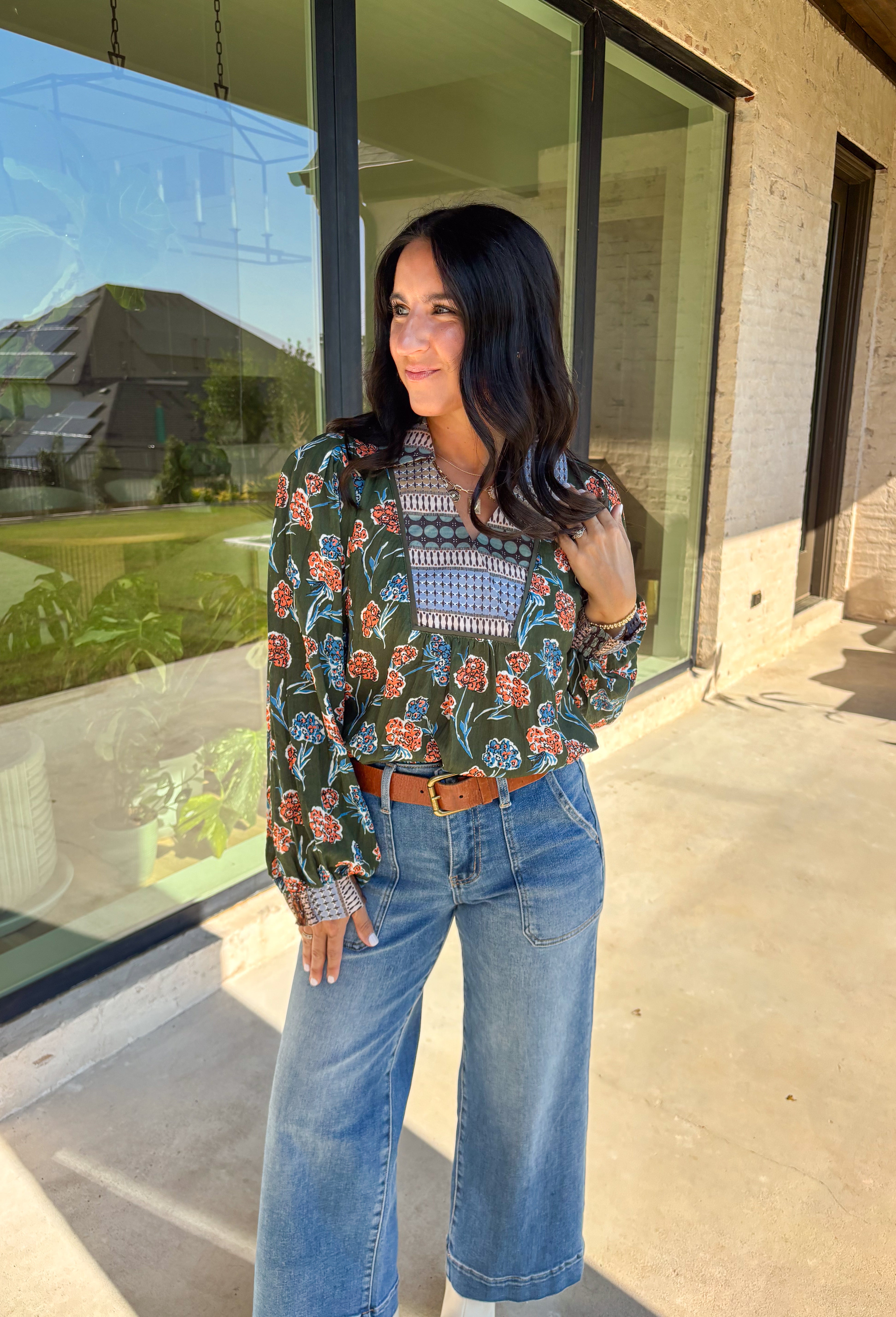 This green long sleeve top is a fresh mix of bold florals and thoughtful detail. Splashed with a colorful floral print in shades of orange, blue, black, and white, it’s balanced with a neutral abstract print along the front and collar for extra visual interest. Smocked sleeves finish the look with a feminine touch, making this blouse a statement piece you’ll love wearing through the season. Lightweight and easy to style, it’s perfect for everything from weekday wear to weekend outings.