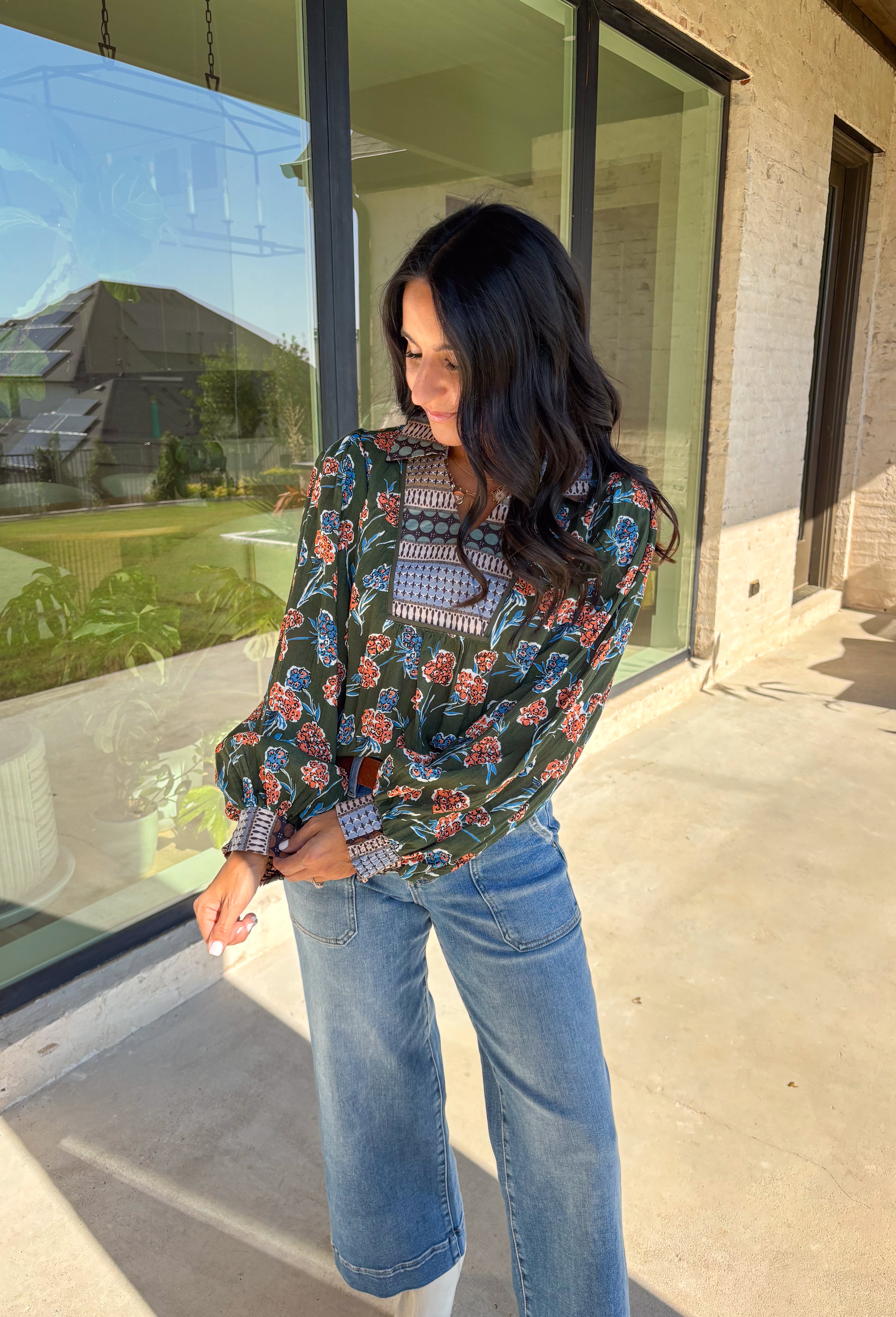 This green long sleeve top is a fresh mix of bold florals and thoughtful detail. Splashed with a colorful floral print in shades of orange, blue, black, and white, it’s balanced with a neutral abstract print along the front and collar for extra visual interest. Smocked sleeves finish the look with a feminine touch, making this blouse a statement piece you’ll love wearing through the season. Lightweight and easy to style, it’s perfect for everything from weekday wear to weekend outings.