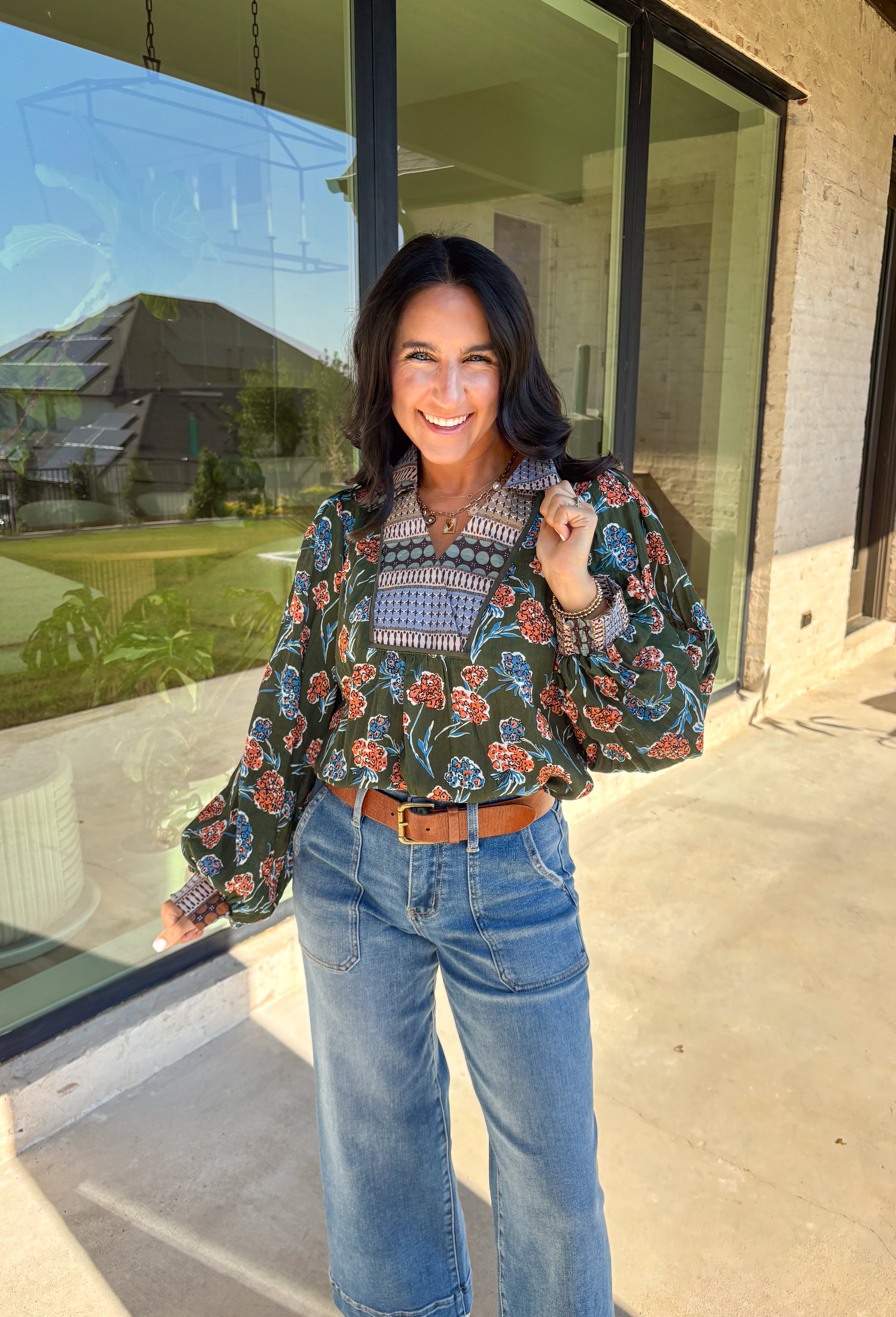 This green long sleeve top is a fresh mix of bold florals and thoughtful detail. Splashed with a colorful floral print in shades of orange, blue, black, and white, it’s balanced with a neutral abstract print along the front and collar for extra visual interest. Smocked sleeves finish the look with a feminine touch, making this blouse a statement piece you’ll love wearing through the season. Lightweight and easy to style, it’s perfect for everything from weekday wear to weekend outings.