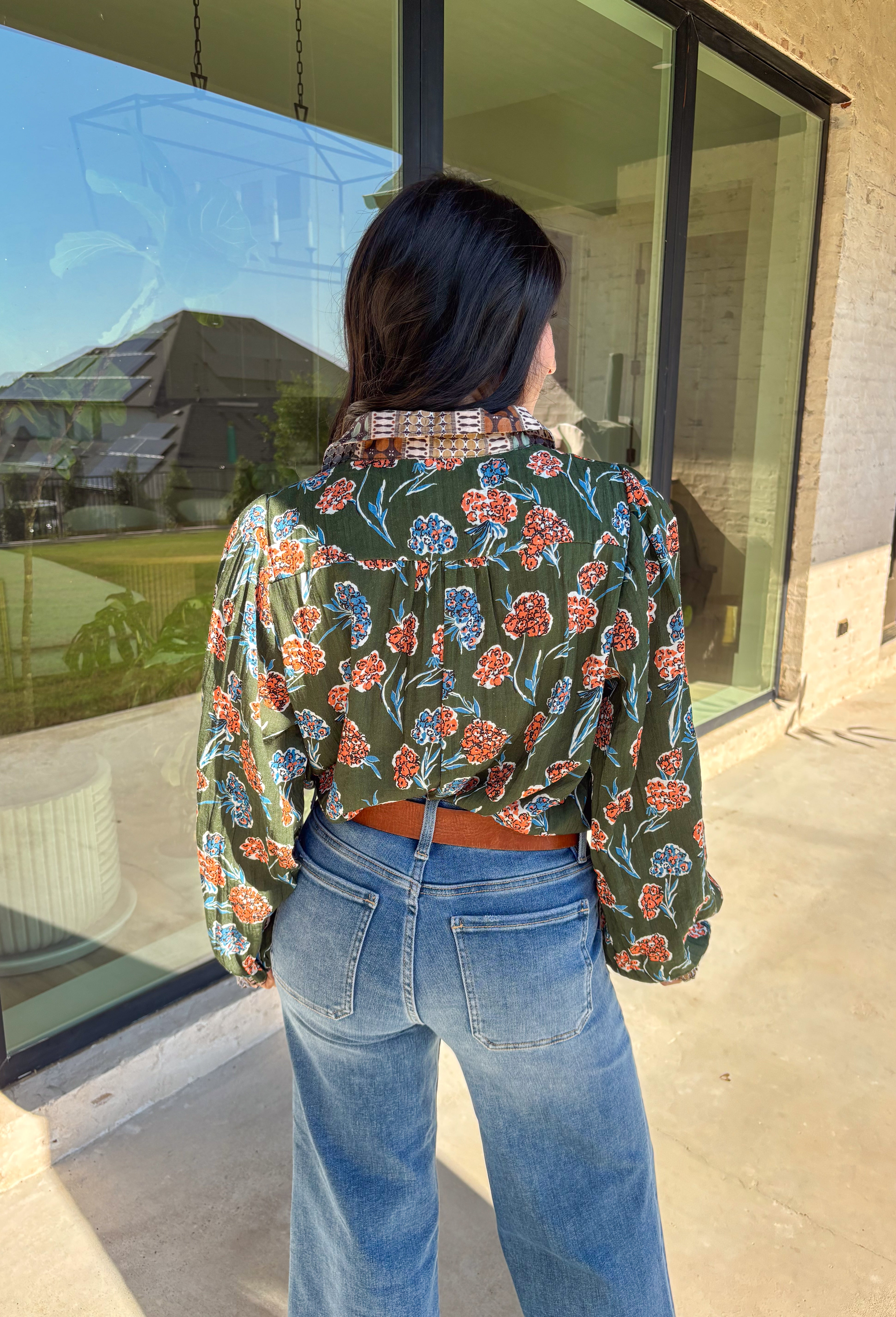 This green long sleeve top is a fresh mix of bold florals and thoughtful detail. Splashed with a colorful floral print in shades of orange, blue, black, and white, it’s balanced with a neutral abstract print along the front and collar for extra visual interest. Smocked sleeves finish the look with a feminine touch, making this blouse a statement piece you’ll love wearing through the season. Lightweight and easy to style, it’s perfect for everything from weekday wear to weekend outings.