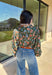 This green long sleeve top is a fresh mix of bold florals and thoughtful detail. Splashed with a colorful floral print in shades of orange, blue, black, and white, it’s balanced with a neutral abstract print along the front and collar for extra visual interest. Smocked sleeves finish the look with a feminine touch, making this blouse a statement piece you’ll love wearing through the season. Lightweight and easy to style, it’s perfect for everything from weekday wear to weekend outings.