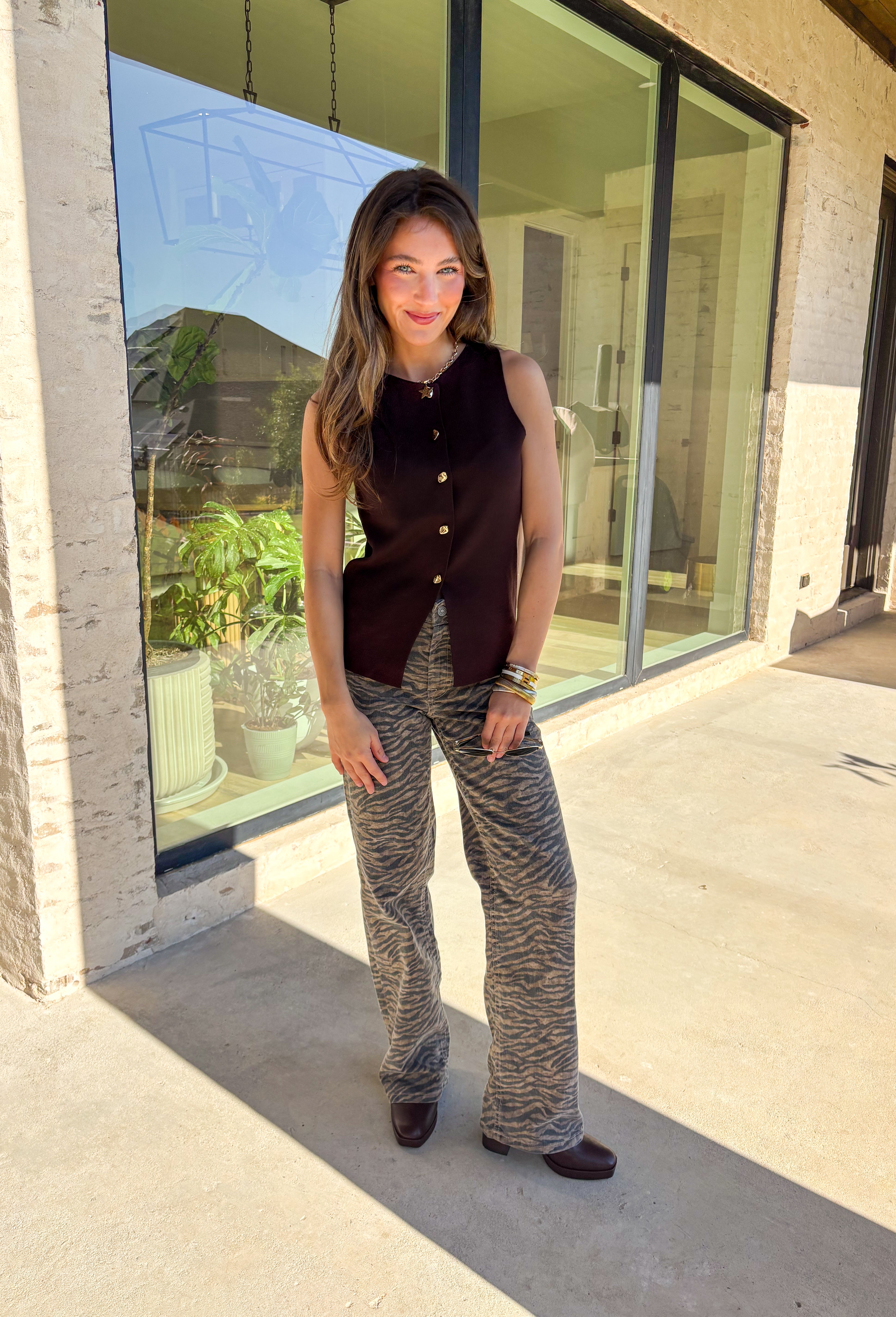 Classic meets modern in this sleeveless brown sweater by Iris. The button-down design is elevated with gold hammered buttons that add a chic, statement touch. Crafted in a soft knit with a lightweight feel, it’s perfect for layering under jackets or wearing solo on warmer days. A versatile piece that easily transitions from casual outings to dressier occasions.