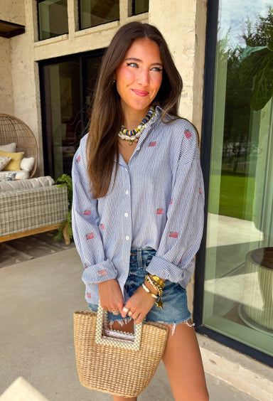 This blue and white stripe button down is the perfect blend of classic style and patriotic charm! Featuring embroidered American flags throughout, it adds a fun, festive touch while still feeling timeless and easy to wear. The collared neckline and button down design give it that effortless, polished look you can style for everything from backyard BBQs to fireworks and holiday weekends. Lightweight and breathable, it’s the perfect layer for all your summer celebrations. 
