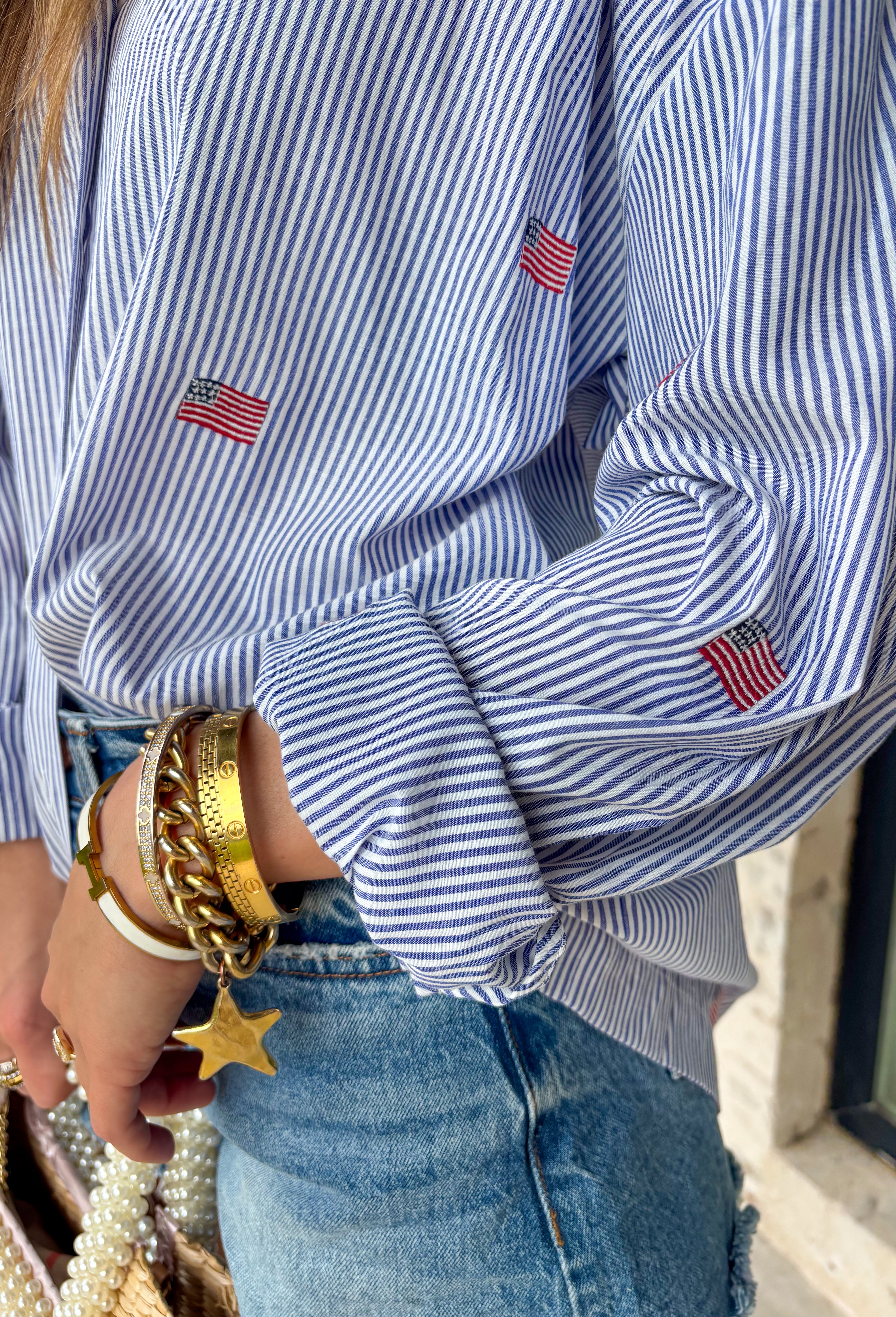 This blue and white stripe button down is the perfect blend of classic style and patriotic charm! Featuring embroidered American flags throughout, it adds a fun, festive touch while still feeling timeless and easy to wear. The collared neckline and button down design give it that effortless, polished look you can style for everything from backyard BBQs to fireworks and holiday weekends. Lightweight and breathable, it’s the perfect layer for all your summer celebrations. 