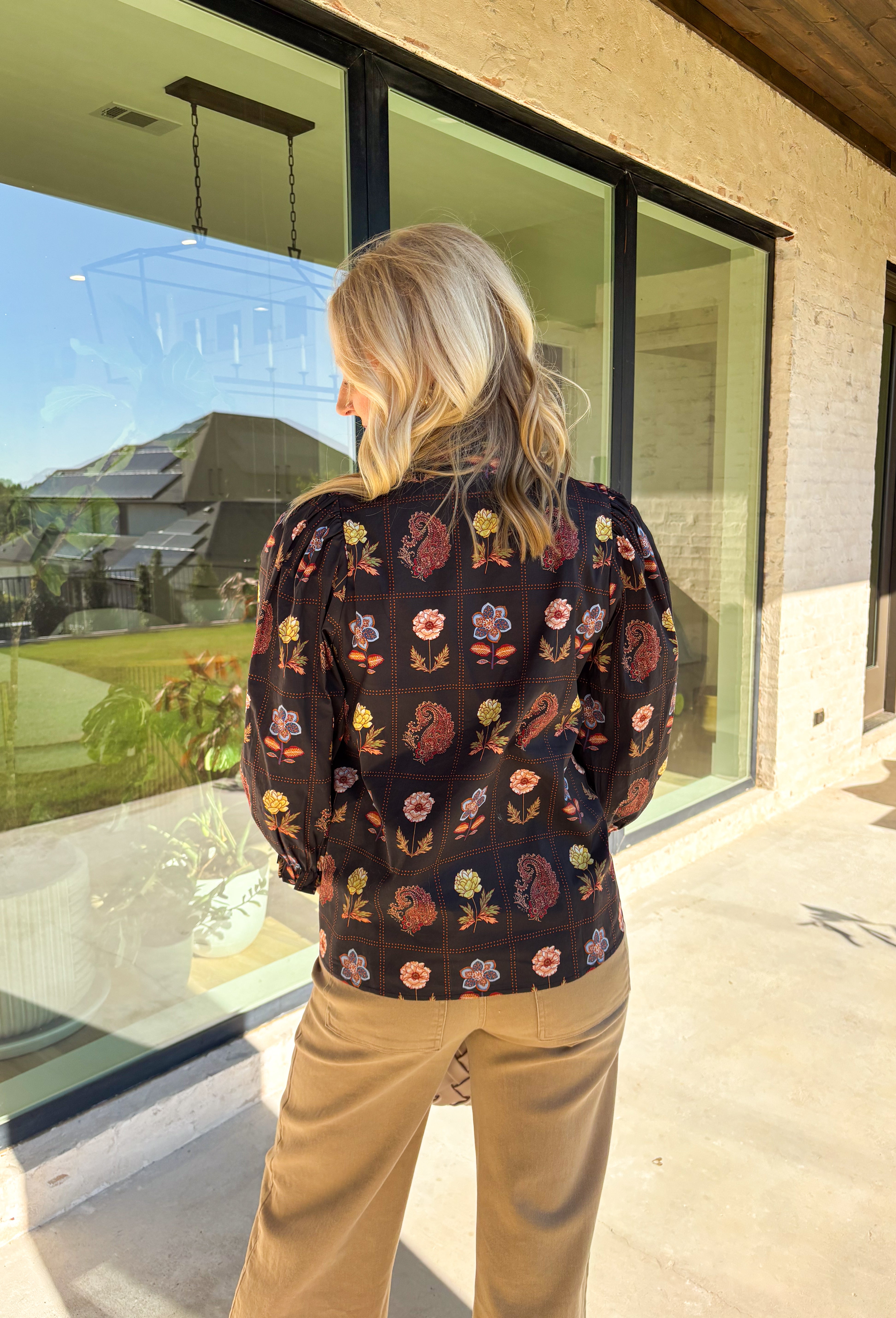 A statement piece for the season, this black top by Entro brings together rich autumn tones and timeless details. Featuring a mix of floral and paisley prints, it’s designed with ¾ puff sleeves, a ruffled high neckline, and a delicate loop-button closure at the front. Elasticated sleeve openings with ruffle trim add a feminine finish. Crafted from soft cotton with a hint of stretch, this top is as comfortable as it is stylish—perfect for dressing up or down this fall.