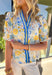 Soft, sunny, and full of spring charm, this off-white short sleeve top by Entro is an easy favorite for the season. Featuring a yellow and blue floral print, it feels bright and cheerful without being overpowering. The coordinating yellow and blue band along the front adds a fun pop of contrast, while the smocked neckline and ruffle sleeves bring a sweet, feminine finish. Crafted from breathable cotton, this top is perfect for warm spring days.