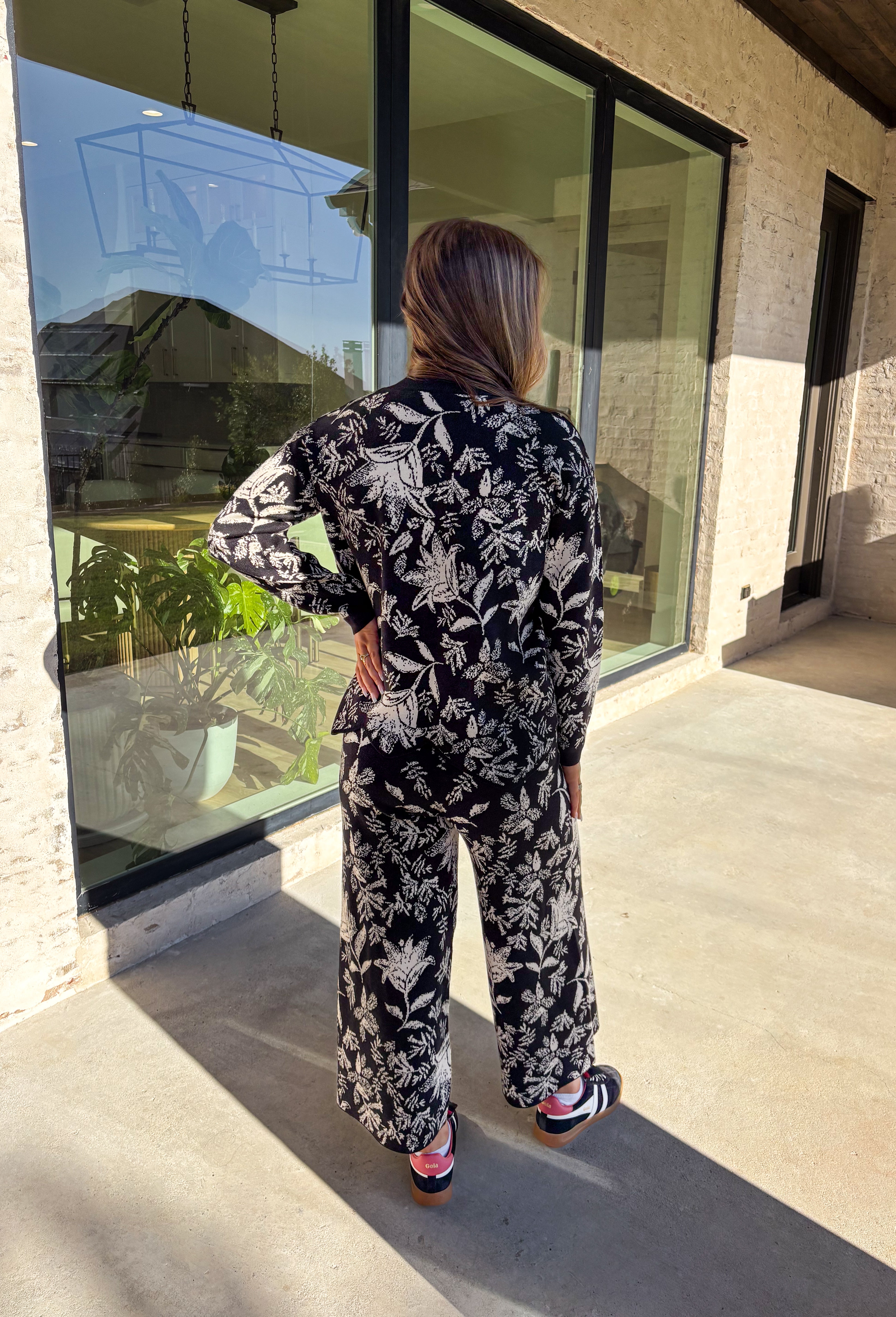 Cozy meets chic in this matching knit set that’s made to turn heads. The black long sleeve top is designed with a cream floral print and finished with a scalloped hem for a sweet touch of detail. Paired with wide leg pants featuring an easy elastic waistband, this set blends lounge-worthy comfort with pulled-together style. Wear the pieces together for a bold coordinated look, or mix and match for endless outfit options.