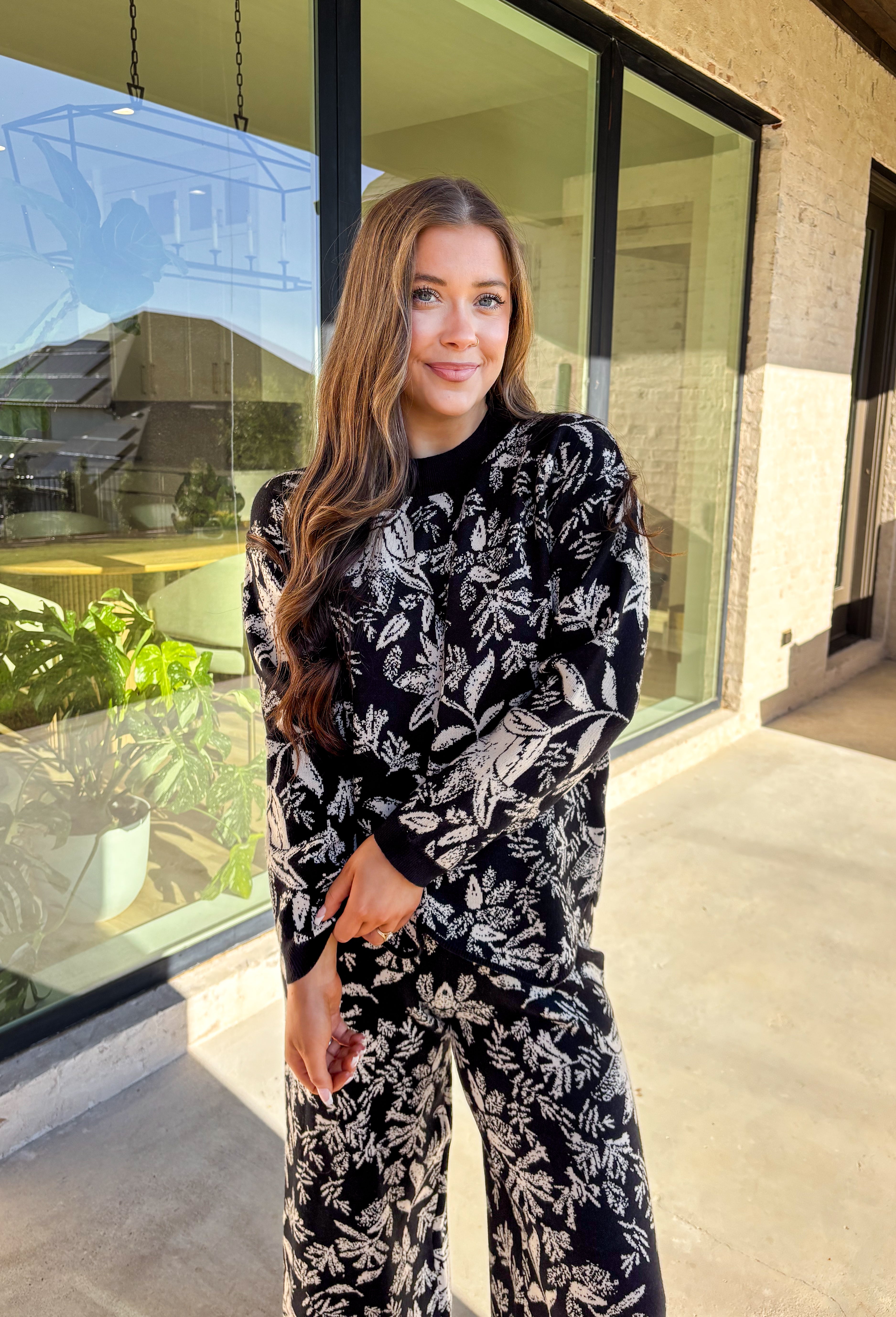 Cozy meets chic in this matching knit set that’s made to turn heads. The black long sleeve top is designed with a cream floral print and finished with a scalloped hem for a sweet touch of detail. Paired with wide leg pants featuring an easy elastic waistband, this set blends lounge-worthy comfort with pulled-together style. Wear the pieces together for a bold coordinated look, or mix and match for endless outfit options.