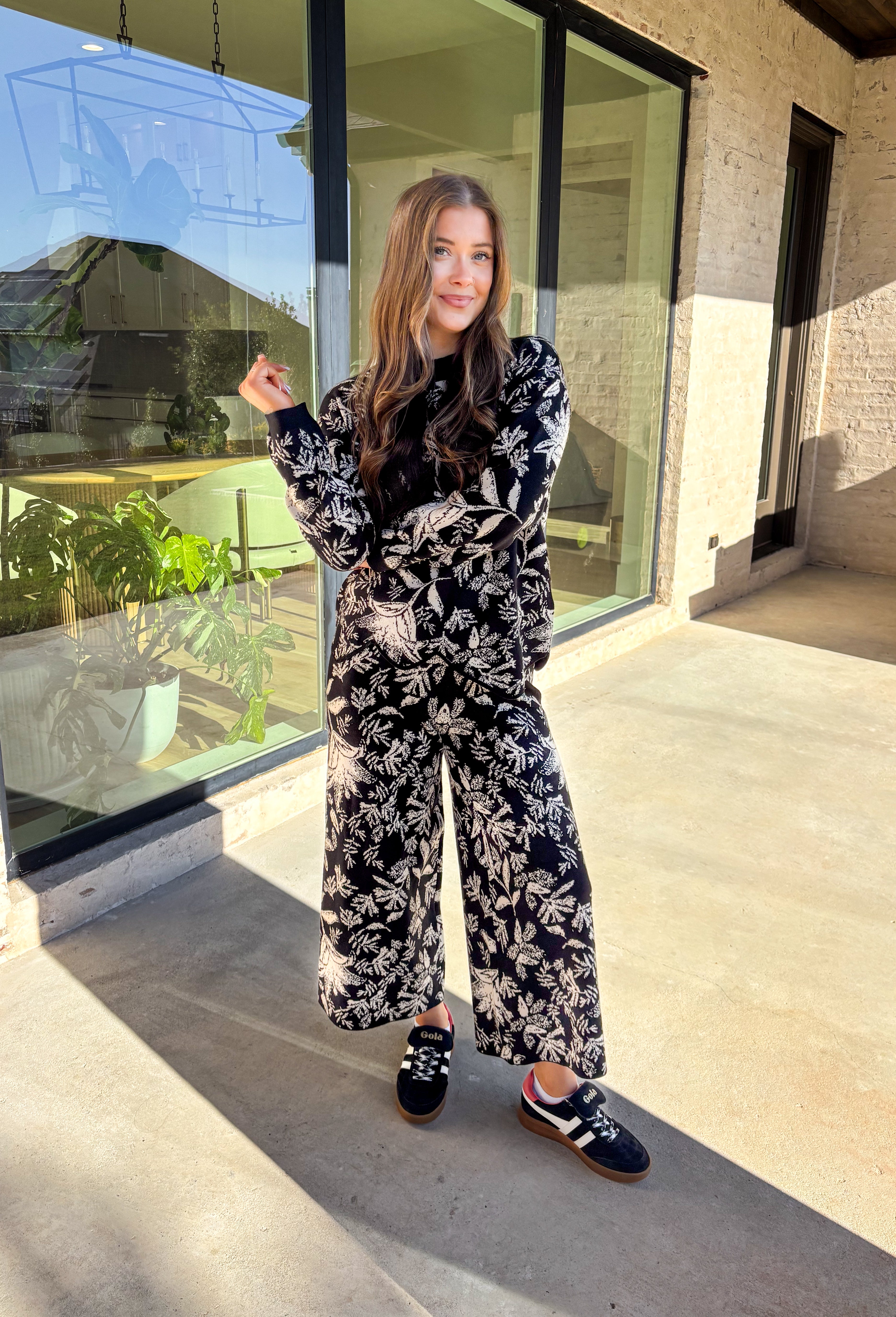 Cozy meets chic in this matching knit set that’s made to turn heads. The black long sleeve top is designed with a cream floral print and finished with a scalloped hem for a sweet touch of detail. Paired with wide leg pants featuring an easy elastic waistband, this set blends lounge-worthy comfort with pulled-together style. Wear the pieces together for a bold coordinated look, or mix and match for endless outfit options.