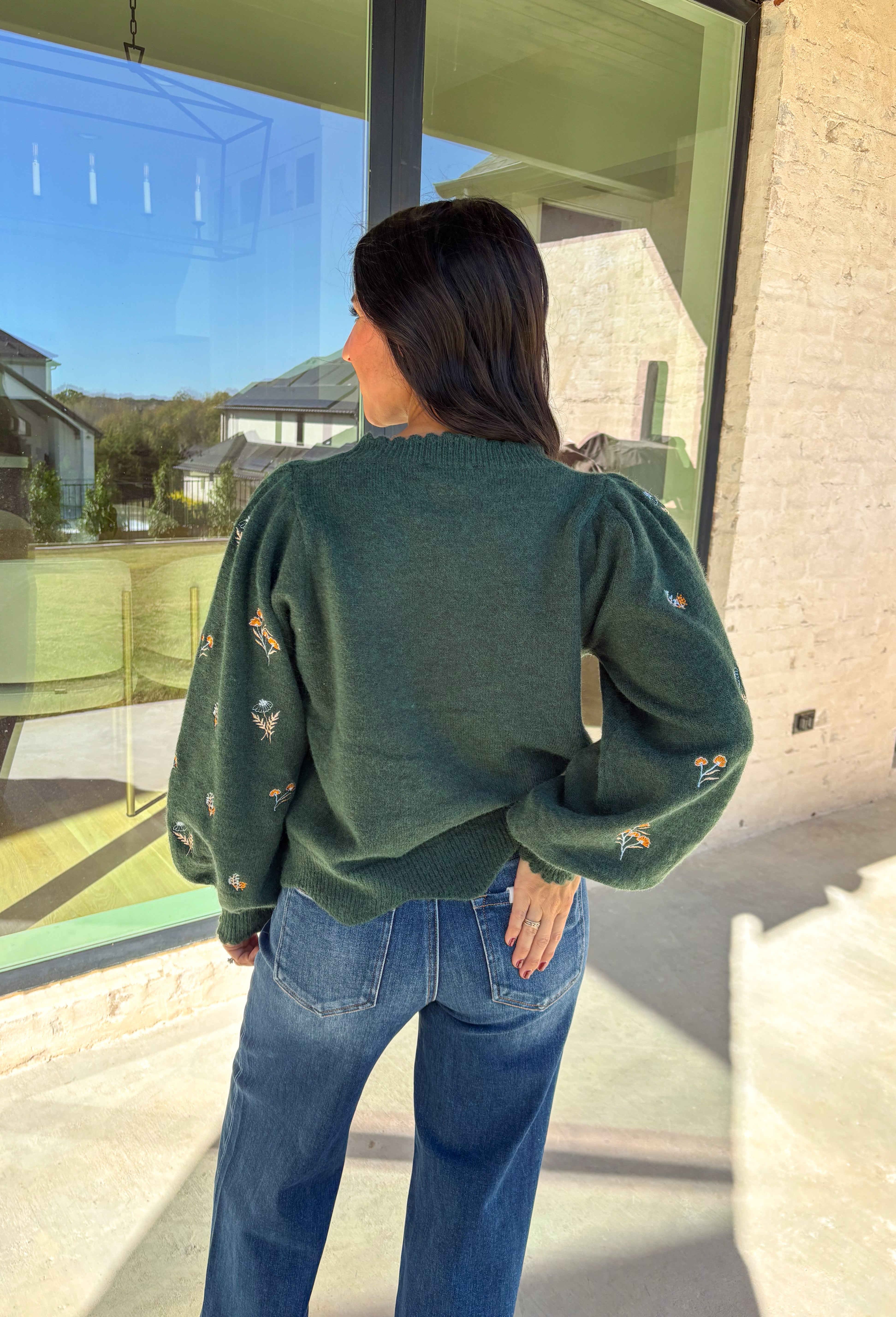This hunter green sweater by Entro brings cozy charm with a touch of detail. The neutral floral embroidery adds soft texture, while the scalloped neckline and hem give it a sweet, feminine finish. Perfect for cool-weather days, this lightweight knit offers that just-right blend of comfort and style for any fall occasion.