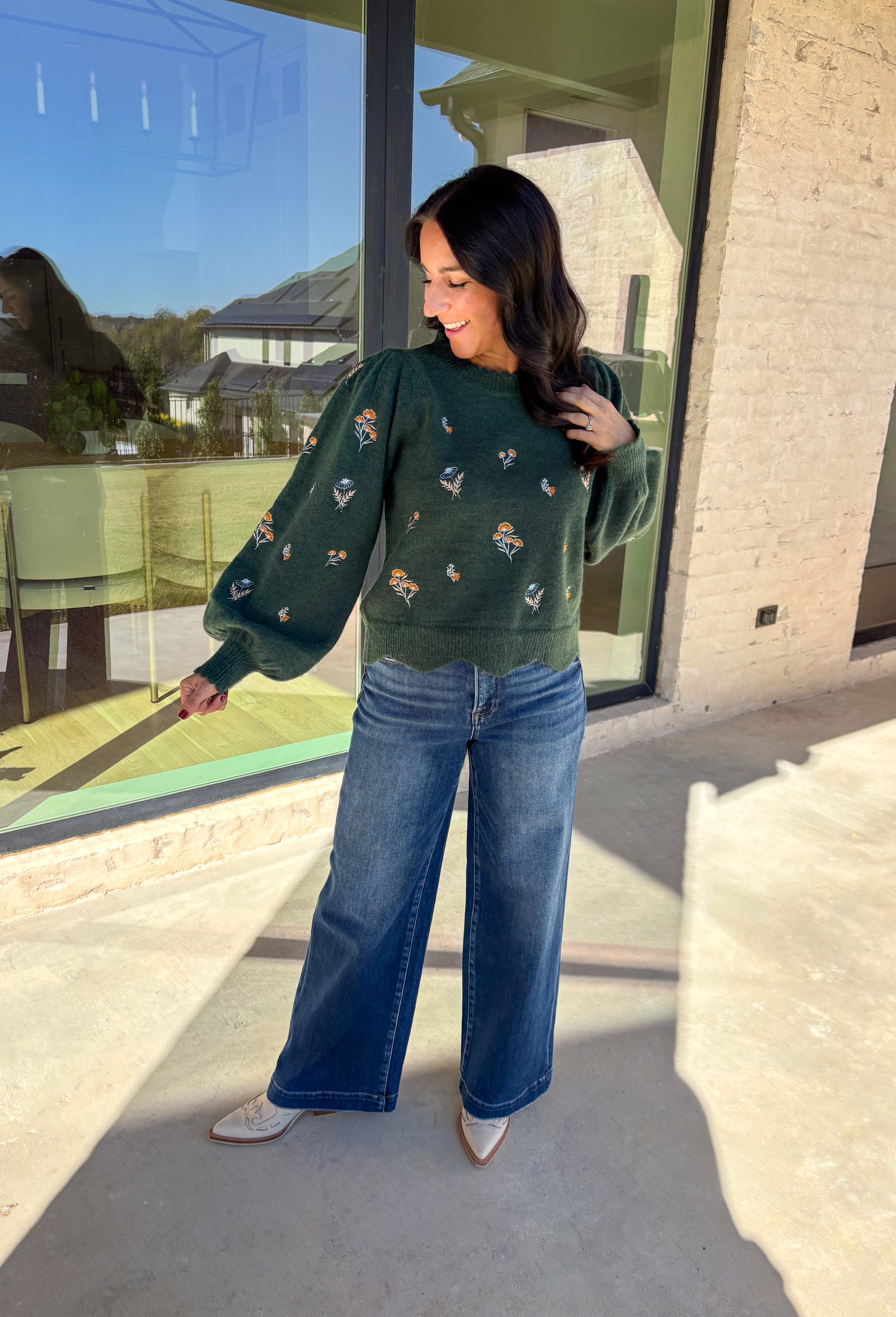 This hunter green sweater by Entro brings cozy charm with a touch of detail. The neutral floral embroidery adds soft texture, while the scalloped neckline and hem give it a sweet, feminine finish. Perfect for cool-weather days, this lightweight knit offers that just-right blend of comfort and style for any fall occasion.
