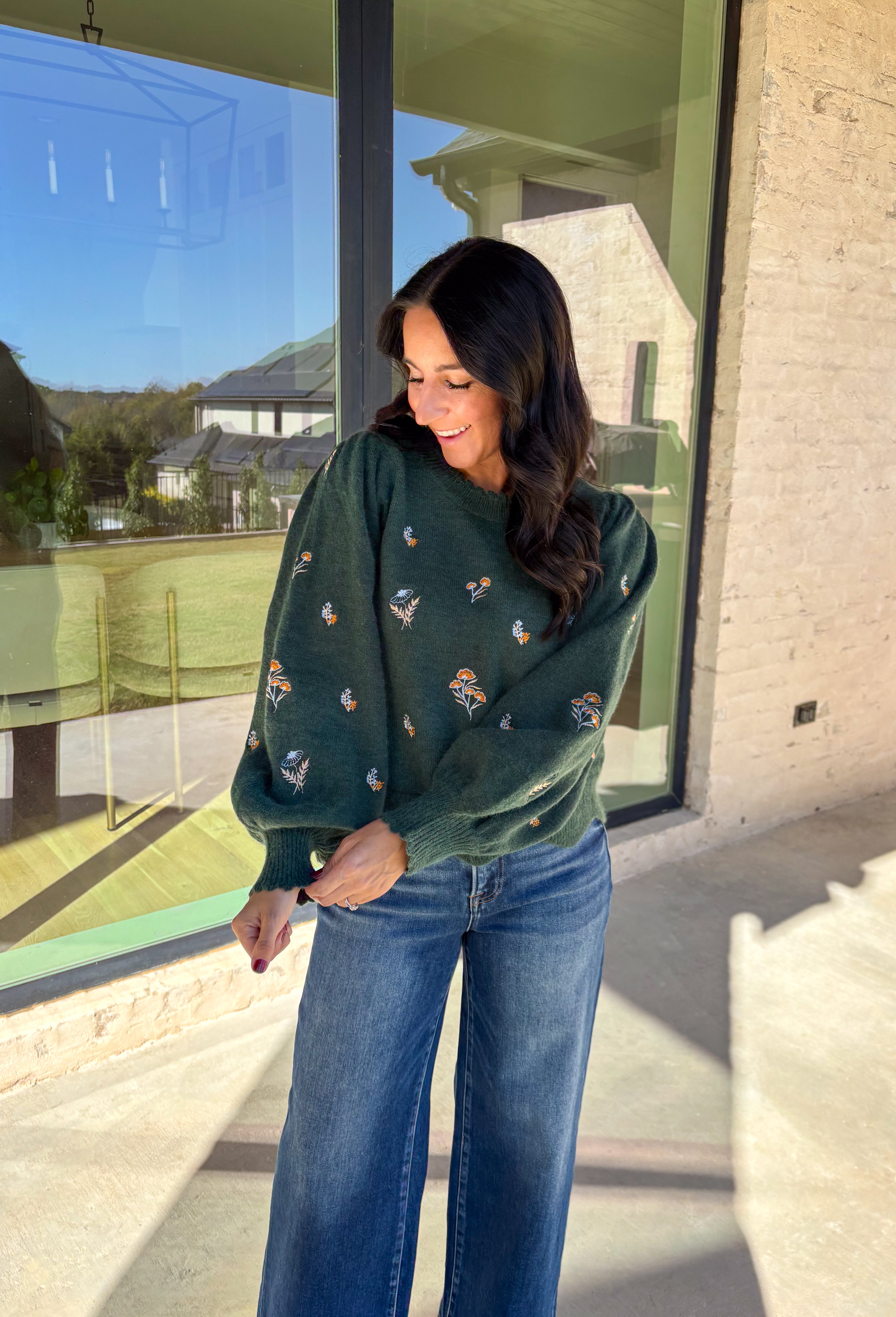This hunter green sweater by Entro brings cozy charm with a touch of detail. The neutral floral embroidery adds soft texture, while the scalloped neckline and hem give it a sweet, feminine finish. Perfect for cool-weather days, this lightweight knit offers that just-right blend of comfort and style for any fall occasion.