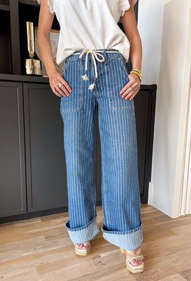 A little classic, a little fun — this medium wash wide leg jean by Lovervet is the perfect blend of polished and relaxed. The crisp white pinstripe print gives it that tailored feel, while the flowy wide leg silhouette keeps it effortlessly cool and on trend. Designed with a flattering high rise and a comfortable elastic back waistband, these jeans offer structure in the front with easy movement in the back. The removable self-tie detail lets you style it your way — cinched and feminine or clean and simple.