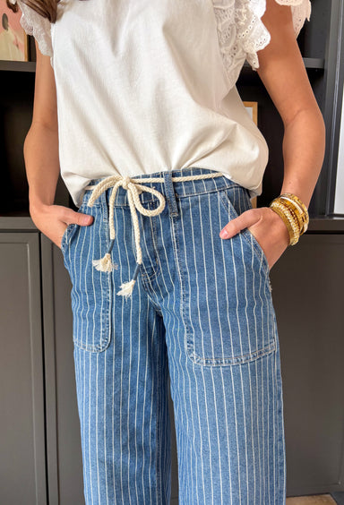 A little classic, a little fun — this medium wash wide leg jean by Lovervet is the perfect blend of polished and relaxed. The crisp white pinstripe print gives it that tailored feel, while the flowy wide leg silhouette keeps it effortlessly cool and on trend. Designed with a flattering high rise and a comfortable elastic back waistband, these jeans offer structure in the front with easy movement in the back. The removable self-tie detail lets you style it your way — cinched and feminine or clean and simple.