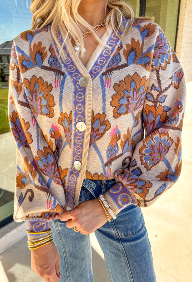 Cozy meets colorful in this tan button-down cardigan. Designed with a floral print in rich shades of periwinkle, purple, pink, and brown, it’s a warm layer that brings instant personality to your fall wardrobe. The long sleeves and soft knit blend keep it extra comfortable, while the button-front closure makes it easy to wear open or closed. Perfect for layering with denim, skirts, or dresses, this cardigan is as versatile as it is charming.