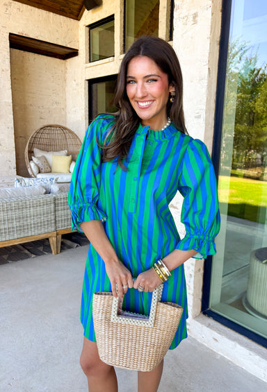 Fresh stripes and easy details make this green and blue dress by Entro a spring must-have. Designed with a striped pattern, it features ¾ length puff sleeves that add a playful, feminine touch. The ruffled band collar and partial button-front closure give it a polished feel, while the self-tie at the back waist creates a flattering, adjustable fit. Fully lined for comfort, this dress is perfect for spring days when you want something effortless, cute, and ready to go.