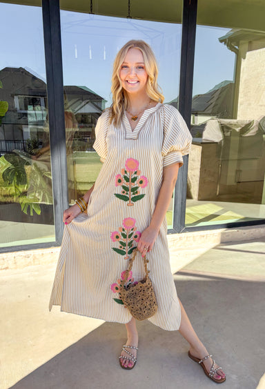 Soft stripes and colorful embroidery make this short sleeve midi dress by Entro a perfect spring standout. Designed with a tan and cream stripe print, it features beautiful floral embroidery along the front with pops of coral, pink, and green for a cheerful seasonal touch. The band collar with a v-cut neckline keeps the look polished yet relaxed, while the midi length and side pockets make it easy and comfortable for all-day wear. You'll find yourself reaching for this dress all season long!