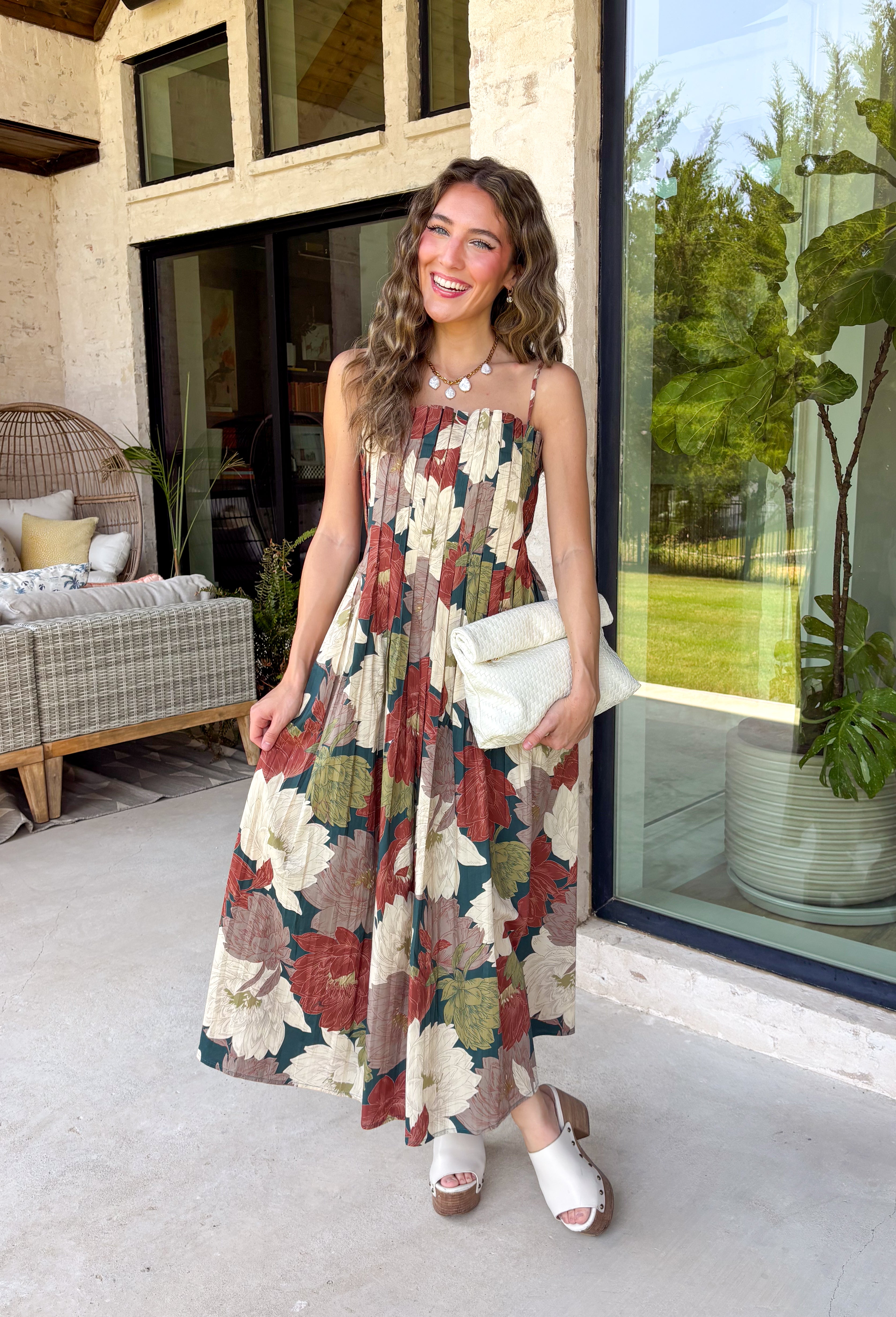 Beautifully feminine and full of rich seasonal color, this floral midi dress is a timeless addition to your fall wardrobe. Designed in a stunning dark teal hue with a gorgeous floral print in warm autumn shades, this dress is perfect for everything from family photos to holiday gatherings. The straight neckline and pleated bodice create an elegant, flattering silhouette, while the adjustable straps and smocked back provide a comfortable, customizable fit. 