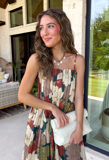 Beautifully feminine and full of rich seasonal color, this floral midi dress is a timeless addition to your fall wardrobe. Designed in a stunning dark teal hue with a gorgeous floral print in warm autumn shades, this dress is perfect for everything from family photos to holiday gatherings. The straight neckline and pleated bodice create an elegant, flattering silhouette, while the adjustable straps and smocked back provide a comfortable, customizable fit. 
