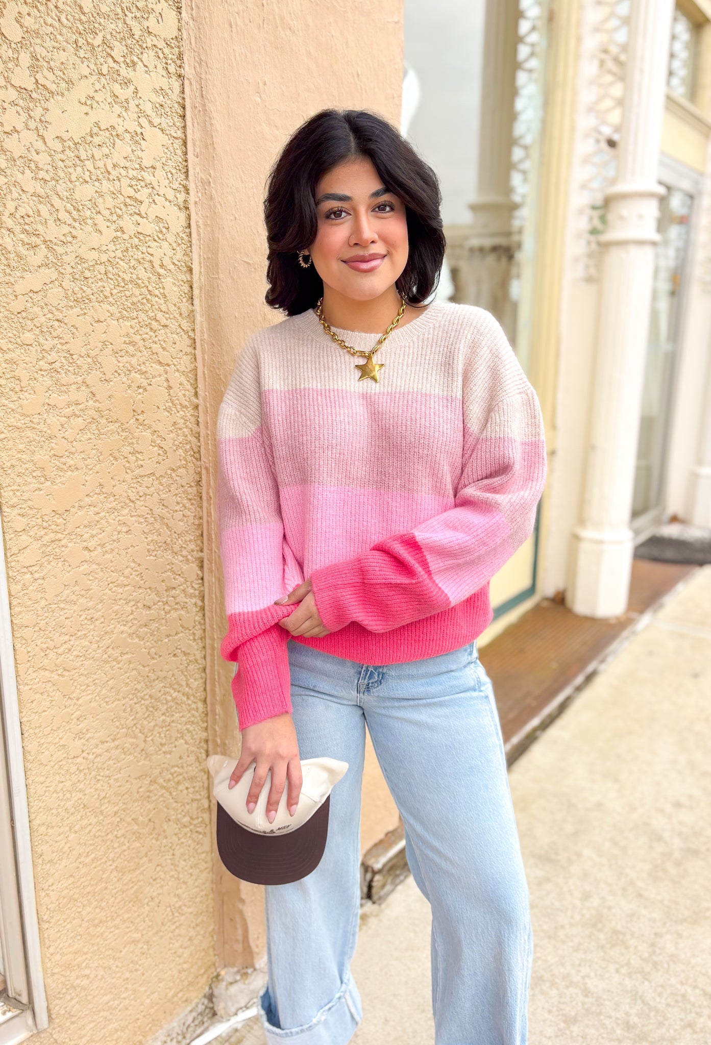 colorblocked pink sweater with different shades of pink and oatmeal styled with a trucker hat and wide leg jeans