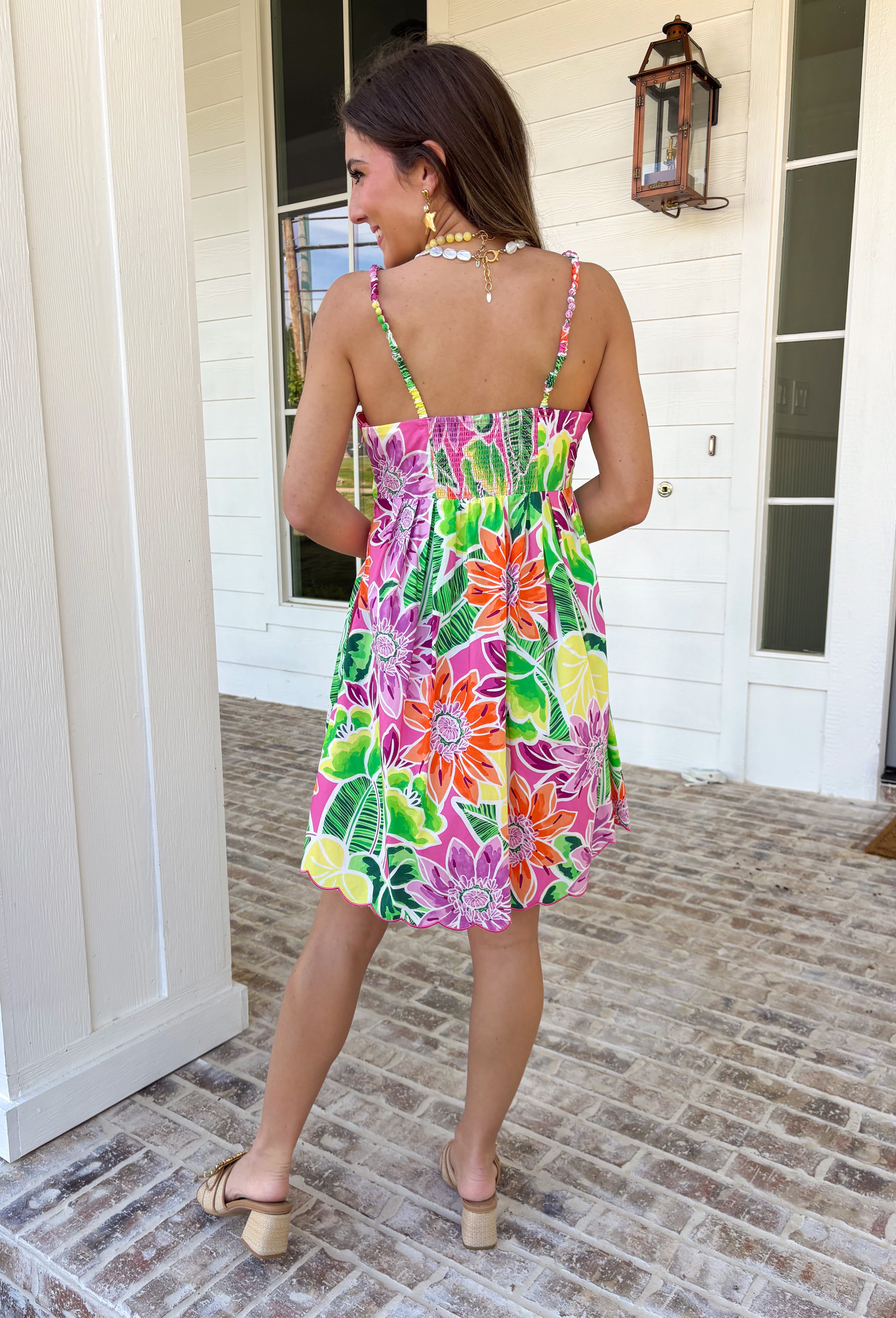 This sleeveless floral dress is bringing all the color and all the confidence. Featuring a bold mix of purple, orange, green, yellow, pink, and white, this beauty is made to stand out in the best way. The scalloped neckline and hem add the sweetest feminine touch, while the fabric-covered knotted bead straps give it that extra detail that feels fun and elevated. Designed with smocking along the back for a comfortable, flattering fit, this fully lined cotton dress is as easy to wear as it is eye-catching. 