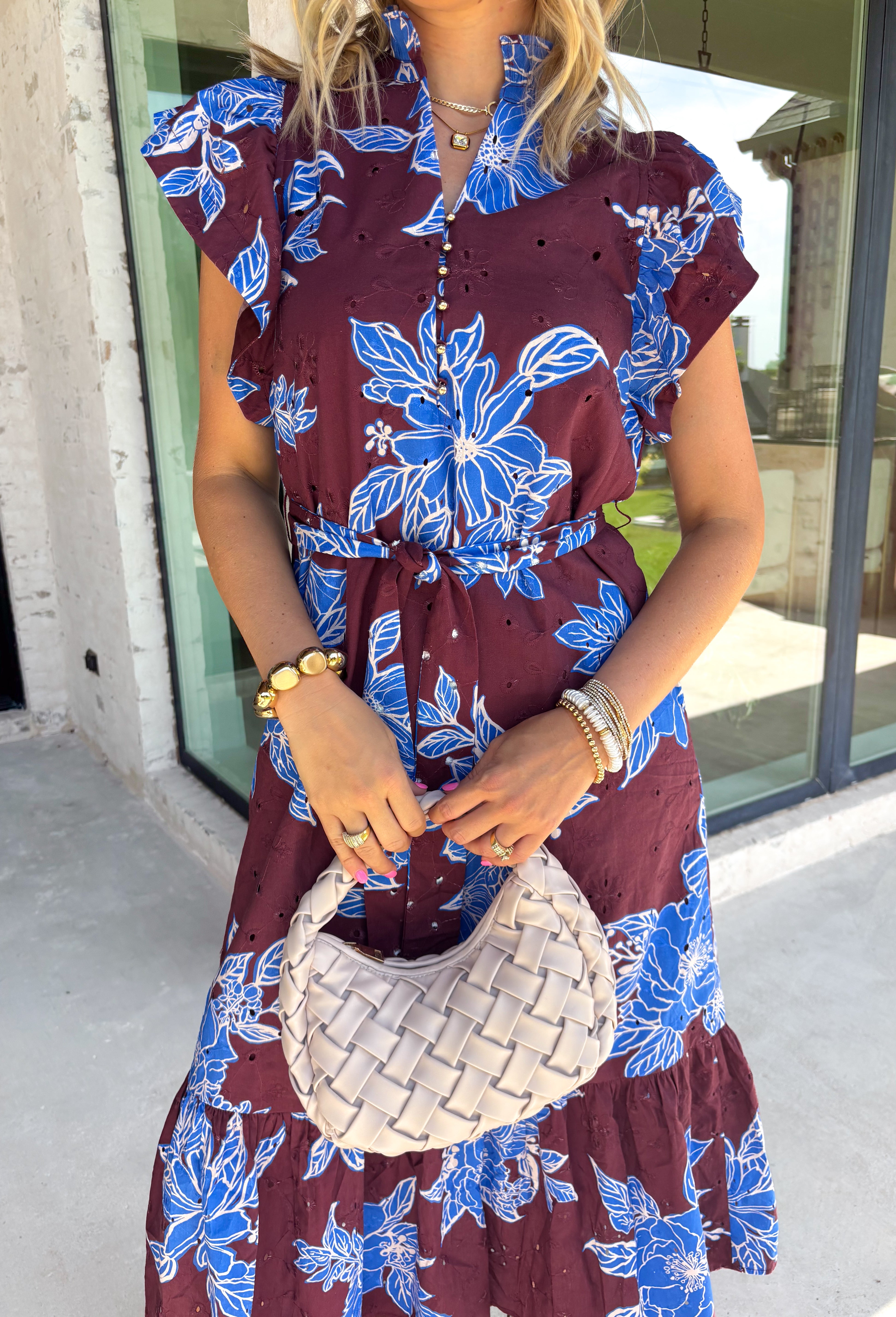 Embrace the beauty of the season in this stunning wine floral midi dress. Featuring a gorgeous blue and white floral print, this feminine dress is perfect for everything on your fall calendar. The self-tie belt cinches the waist for a flattering silhouette, while the ruffle sleeves and ruffle hem add soft movement and romantic charm. Finished with a button-down front, side pockets, and a fully lined design, this timeless cotton dress.