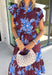 Embrace the beauty of the season in this stunning wine floral midi dress. Featuring a gorgeous blue and white floral print, this feminine dress is perfect for everything on your fall calendar. The self-tie belt cinches the waist for a flattering silhouette, while the ruffle sleeves and ruffle hem add soft movement and romantic charm. Finished with a button-down front, side pockets, and a fully lined design, this timeless cotton dress.