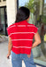 Bring timeless style and cozy comfort to your fall wardrobe with this classic sweater from Day + Moon. Designed in a vibrant red knit with crisp white stripes, this short sleeve sweater is the perfect blend of polished and playful. The cozy turtleneck adds warmth for cooler days, while the soft knit fabric makes it comfortable enough for all-day wear. Whether you're headed to work, a football game, or a weekend coffee date, this versatile sweater is an easy favorite for the season.