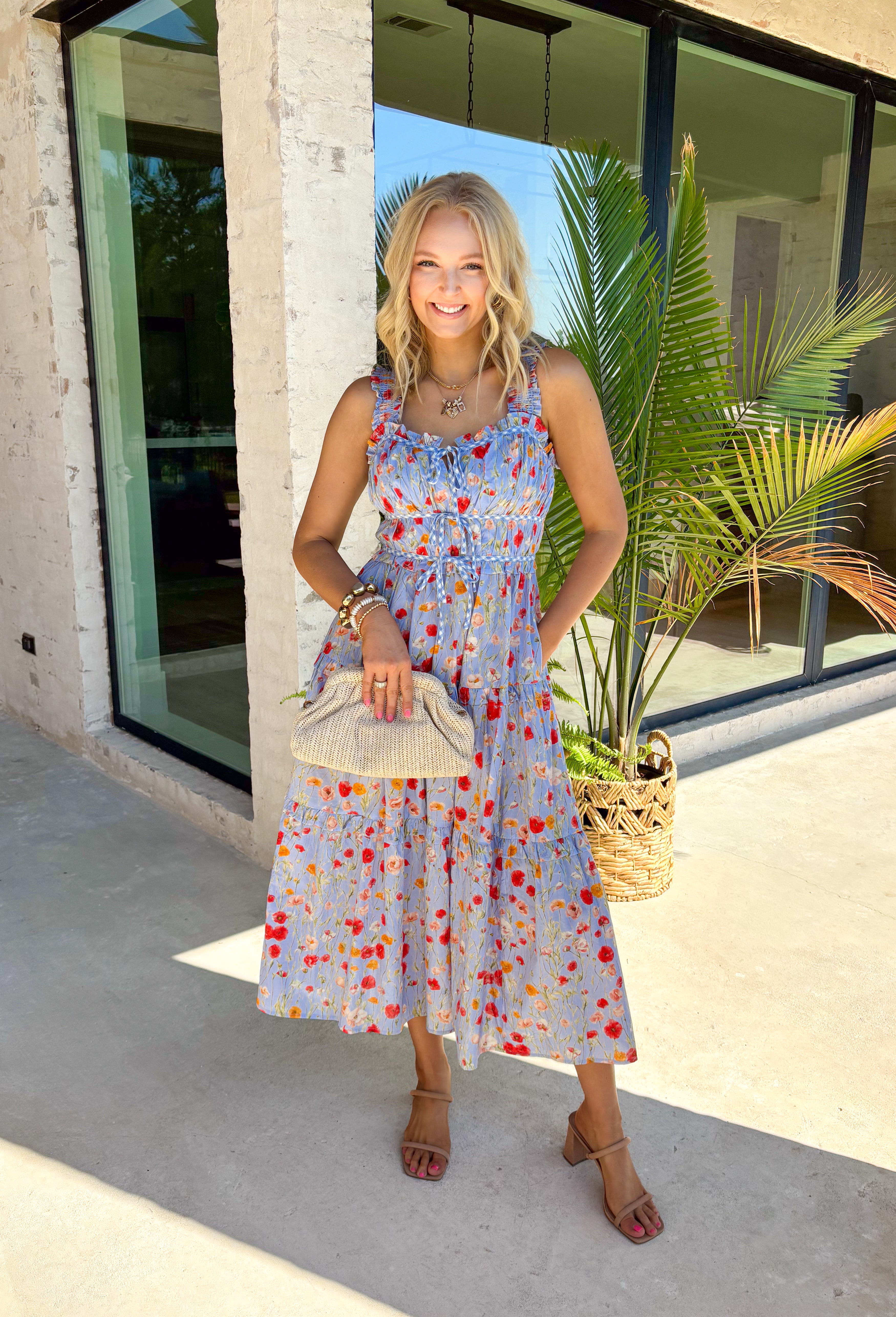 This sleeveless light blue midi dress by Entro is giving major spring picnic energy. With a colorful floral print in pops of red, mustard, and light pink, it’s bright, cheerful, and made for sunny days. The blue and white gingham trim along the top adds the cutest contrast, and the three front tie details bring in that extra sweet, feminine touch we can’t get enough of. 