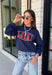 Bring a little extra luck to your cozy season with this playful graphic sweatshirt. Featuring "Lucky" in rust lettering accented with whimsical stars and outlined by a light blue circle, this navy pullover adds the perfect pop of color to your everyday wardrobe. The fleece-lined interior keeps you warm and comfortable, making it the perfect choice for football weekends, coffee runs, casual days, and cozy nights in. It's an easy favorite you'll be reaching for all fall and winter long.