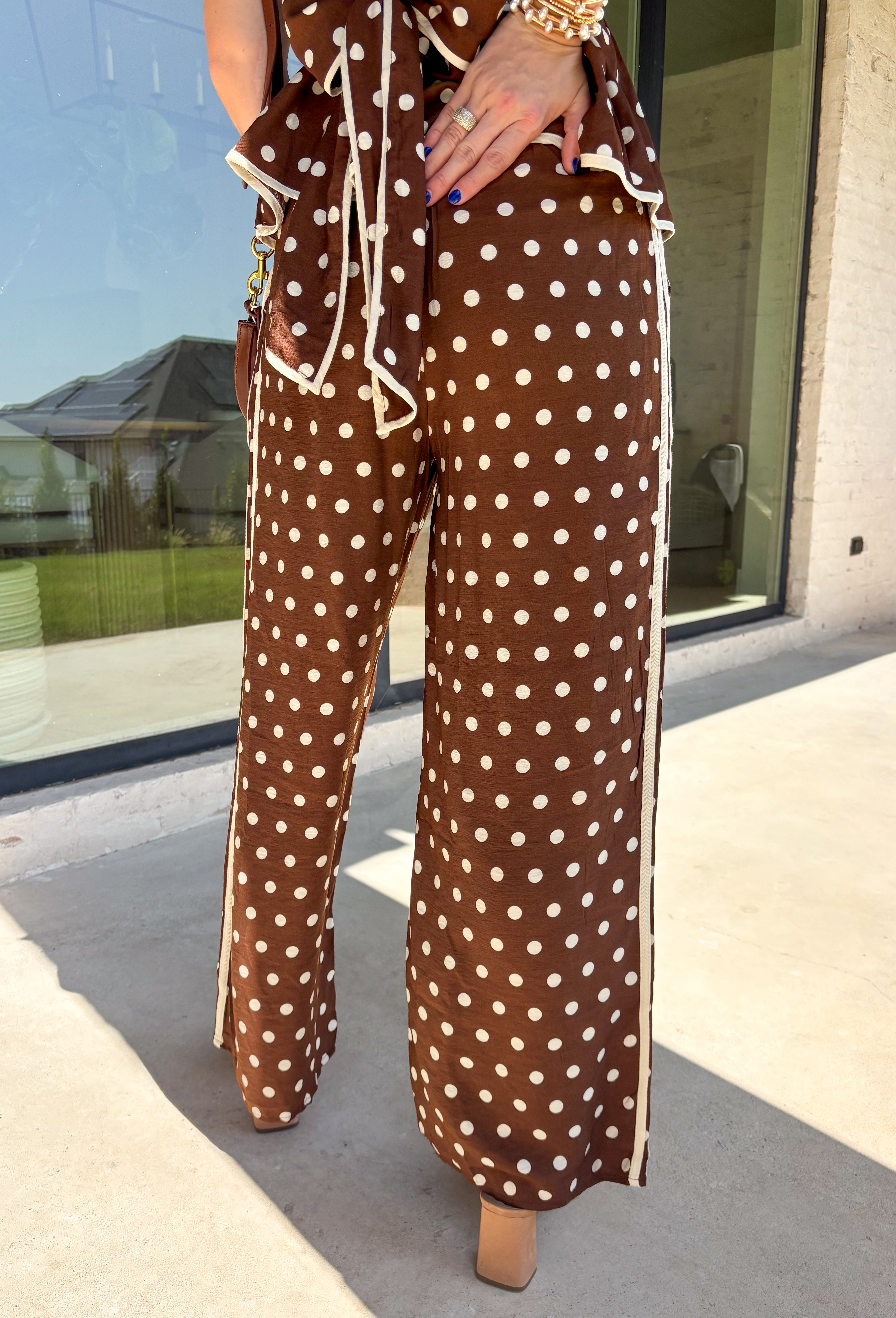 Make a statement from the bottom up with these brown and cream polka dot pants from Entro. The warm brown background paired with classic cream polka dots gives them a playful look that still works beautifully with your favorite fall neutrals. An elasticated waist with a self-tie keeps the fit comfortable and adjustable, while contrast trim along the sides adds an unexpected finishing touch. 