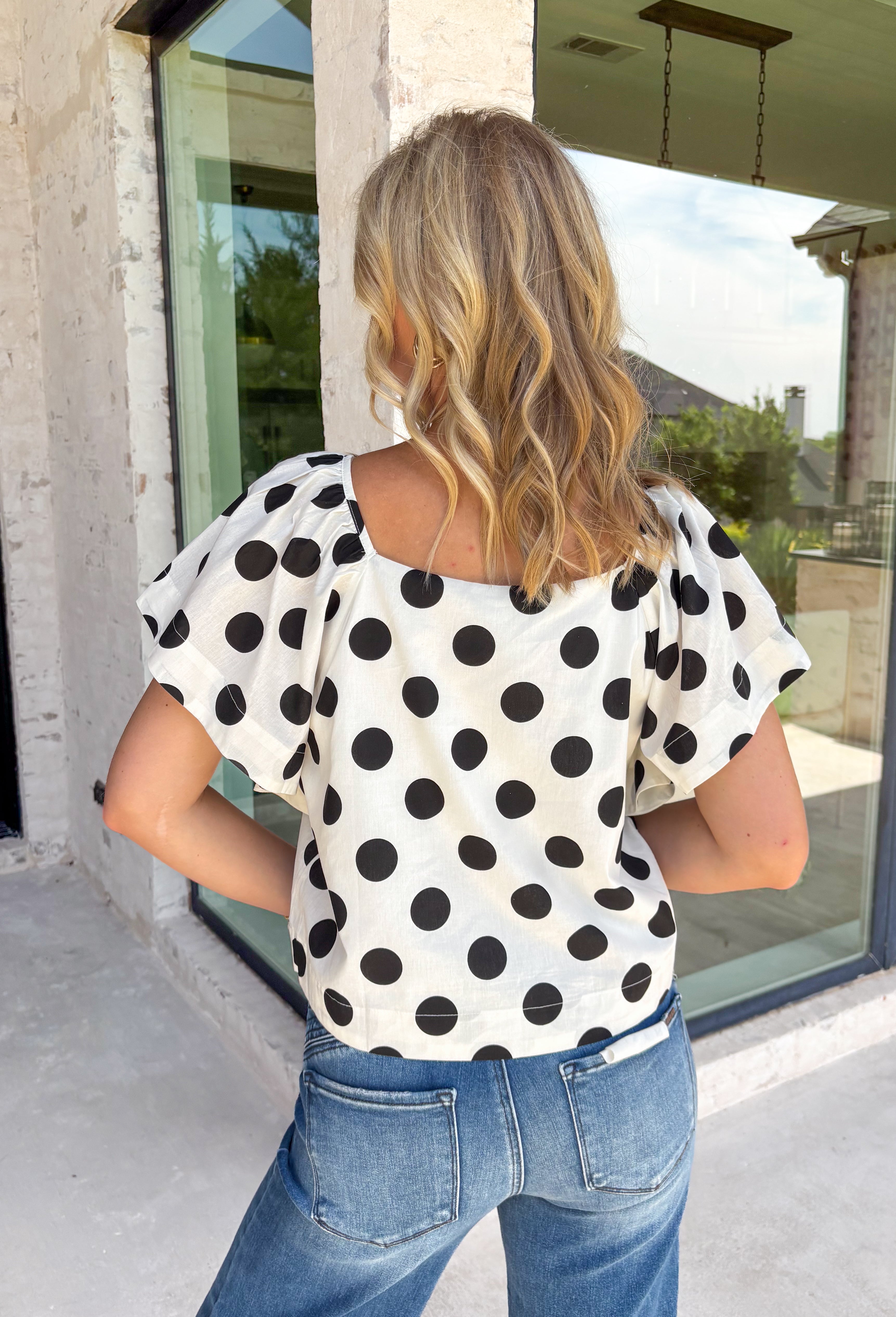 This off white polka dot top is the perfect blend of timeless and on-trend! The classic black polka dot print never goes out of style, while the statement sleeves add a fashion-forward touch that instantly elevates your look. Crafted from breathable cotton, it's lightweight enough to wear now and easy to layer under jackets and cardigans as the seasons change. Whether you're heading to the office, meeting friends for lunch, or dressing up your favorite denim, this top makes looking polished feel effortless.
