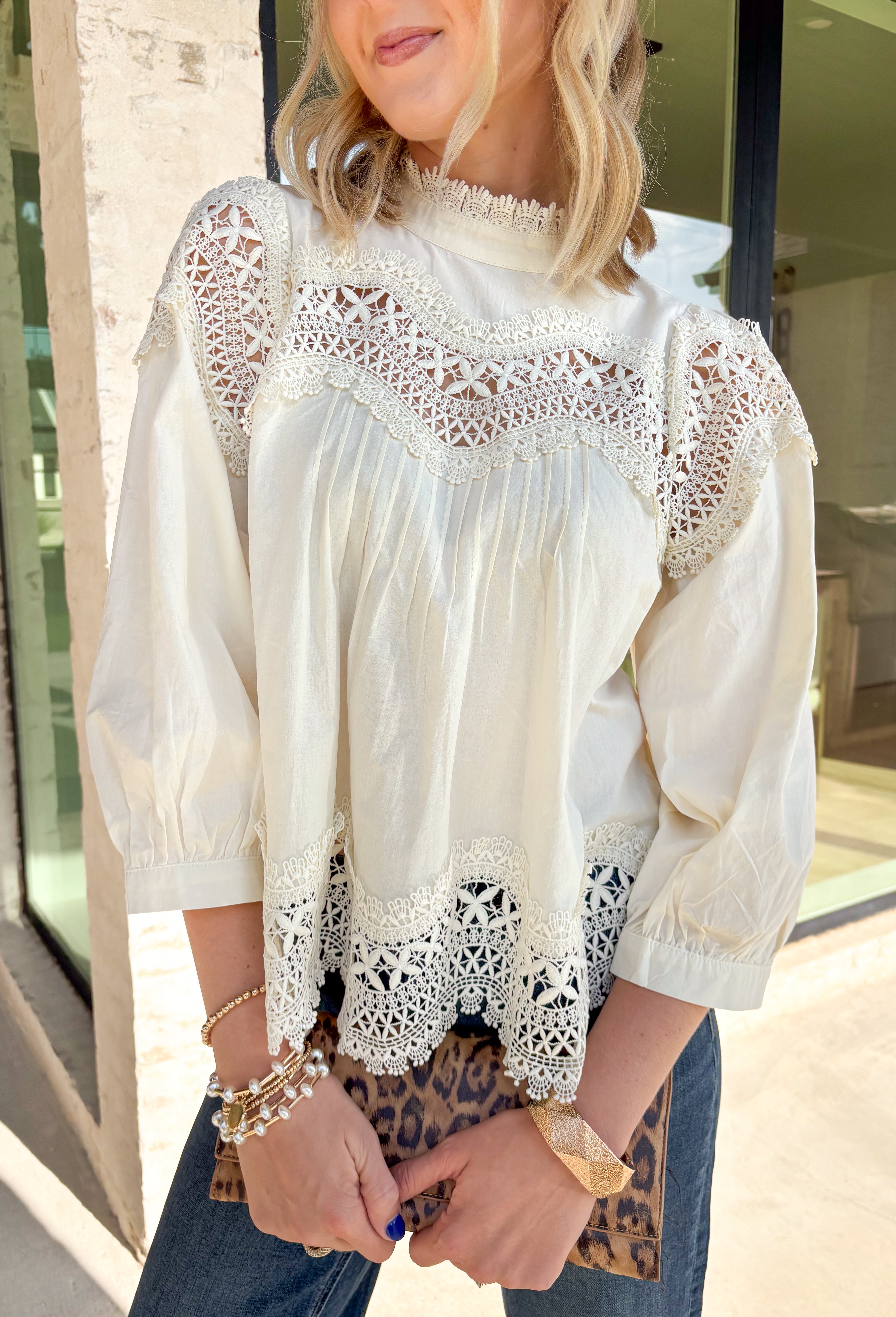 Delicate details and timeless style come together beautifully in this romantic boho-inspired blouse. Crafted from soft cream cotton, this feminine top is adorned with intricate crochet lace throughout, creating a look that's effortlessly elegant while still feeling easy to wear. The high ruffle neckline and scalloped lace accents along the yoke, sleeves, and hem add beautiful texture and vintage-inspired charm, while the keyhole button closure at the back completes the look with a graceful finishing touch. 