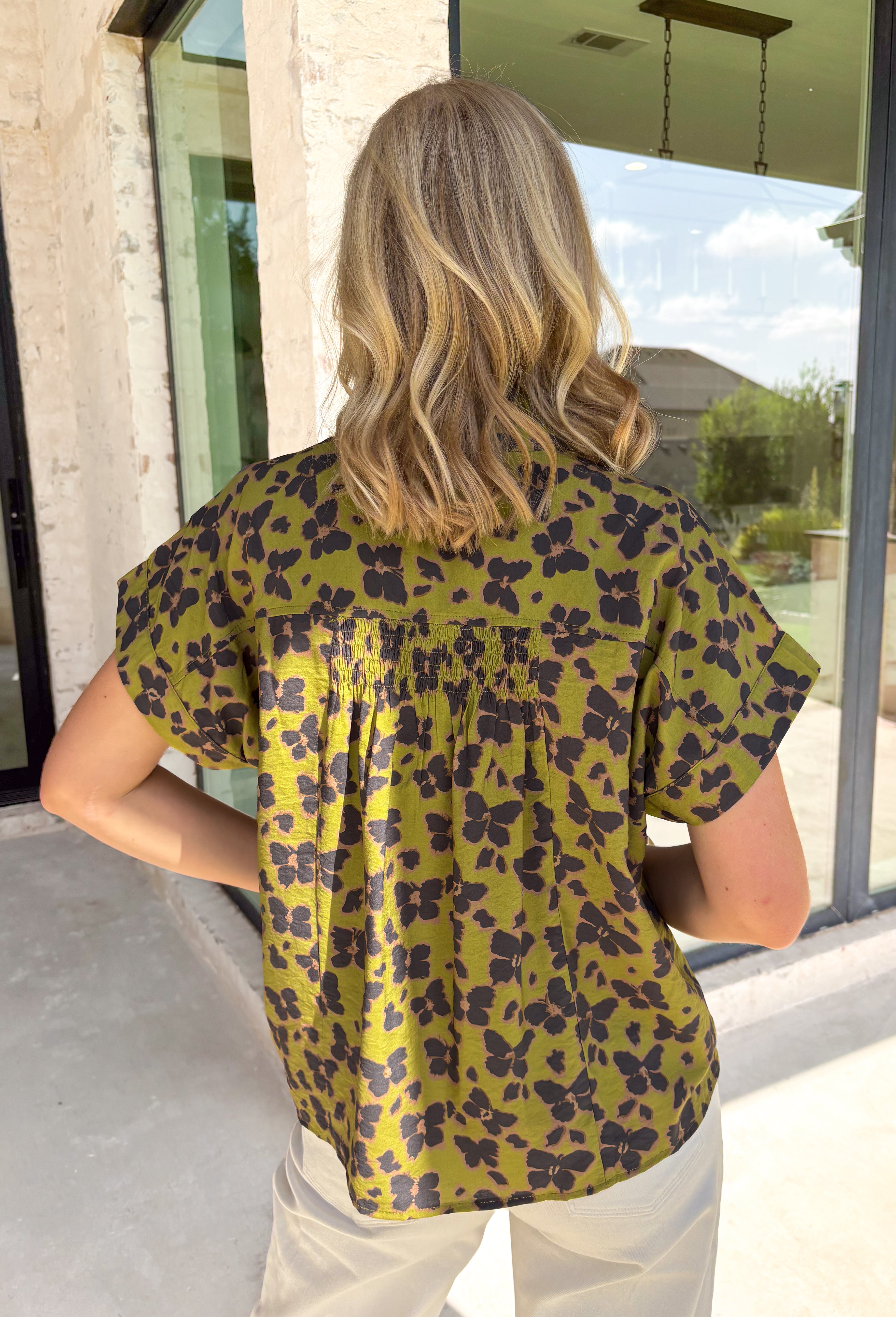 Bring a whimsical touch to your fall wardrobe with this beautifully printed butterfly blouse. Designed in a rich olive green with a striking black butterfly print, this lightweight cotton top offers the perfect balance of playful and polished. The subtle ruffle neckline adds a soft feminine touch, while the button-front detail gives it a timeless feel that's easy to dress up or down.