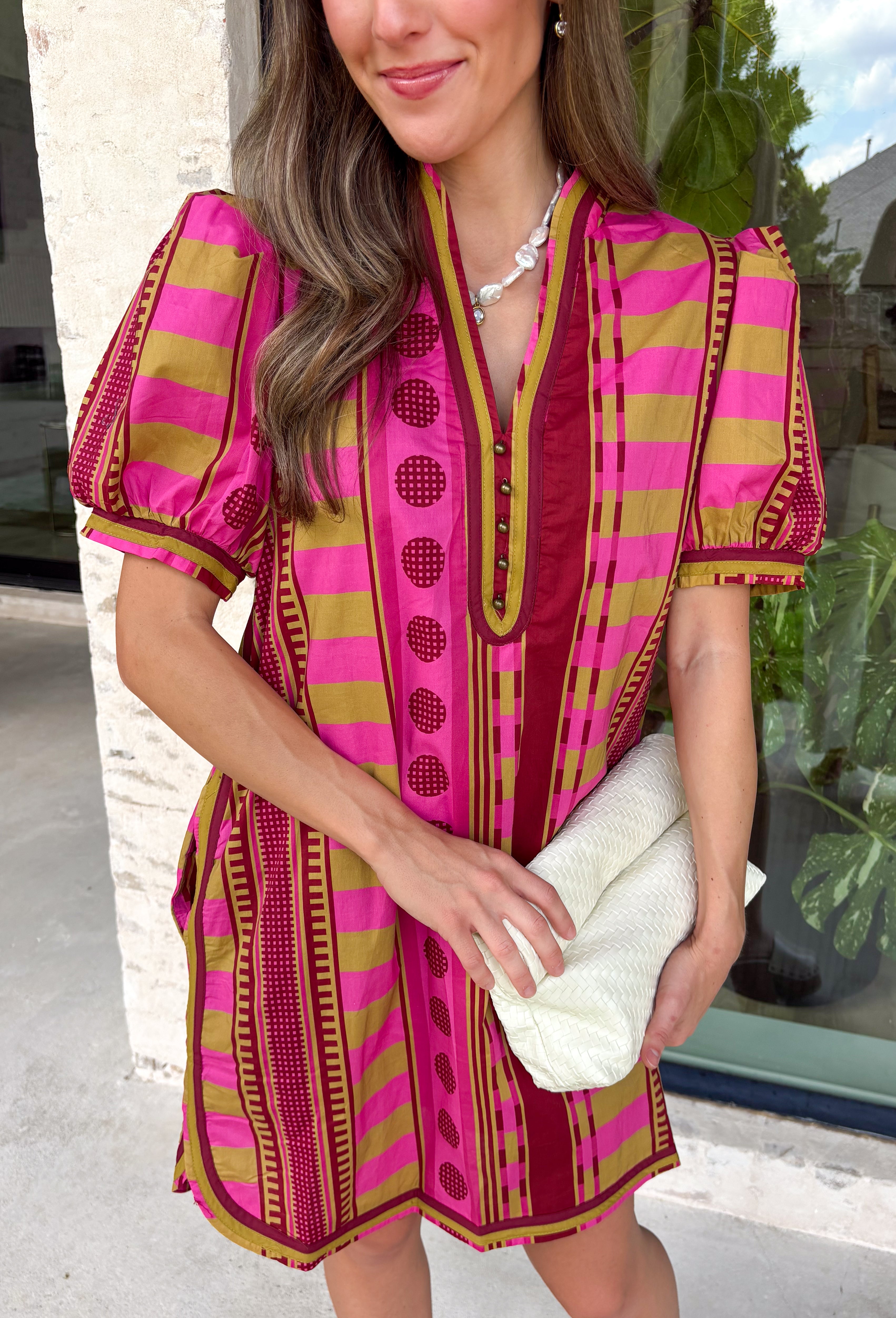 Make a statement this season in this beautifully detailed dress from Entro. Featuring a unique mix of stripes and polka dots in rich shades of plum, burgundy, and olive, this eye-catching dress is full of playful charm with a timeless feel. The flattering v-neckline is accented with decorative front button details, while contrast trim adds an extra touch of personality. 