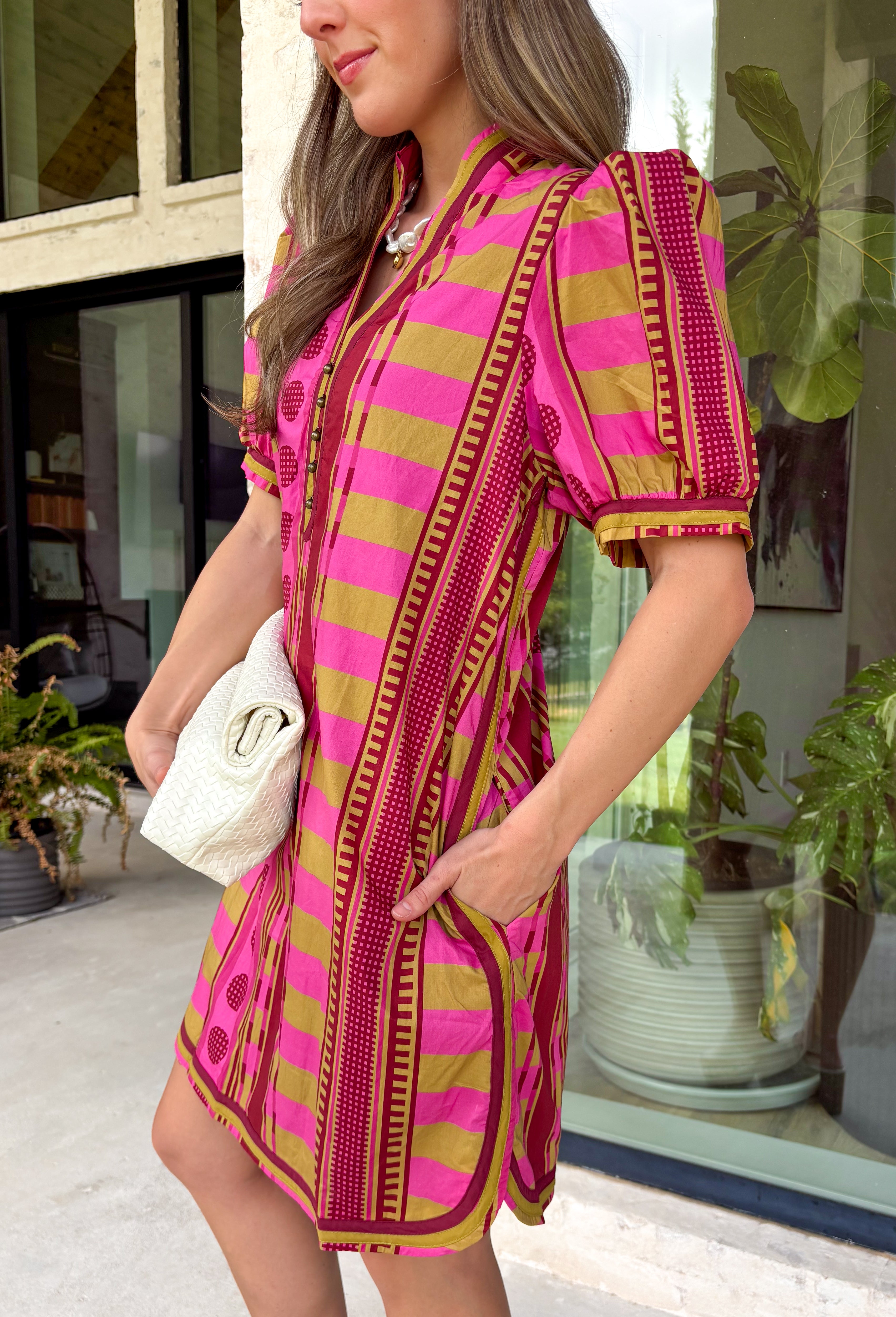 Make a statement this season in this beautifully detailed dress from Entro. Featuring a unique mix of stripes and polka dots in rich shades of plum, burgundy, and olive, this eye-catching dress is full of playful charm with a timeless feel. The flattering v-neckline is accented with decorative front button details, while contrast trim adds an extra touch of personality. 