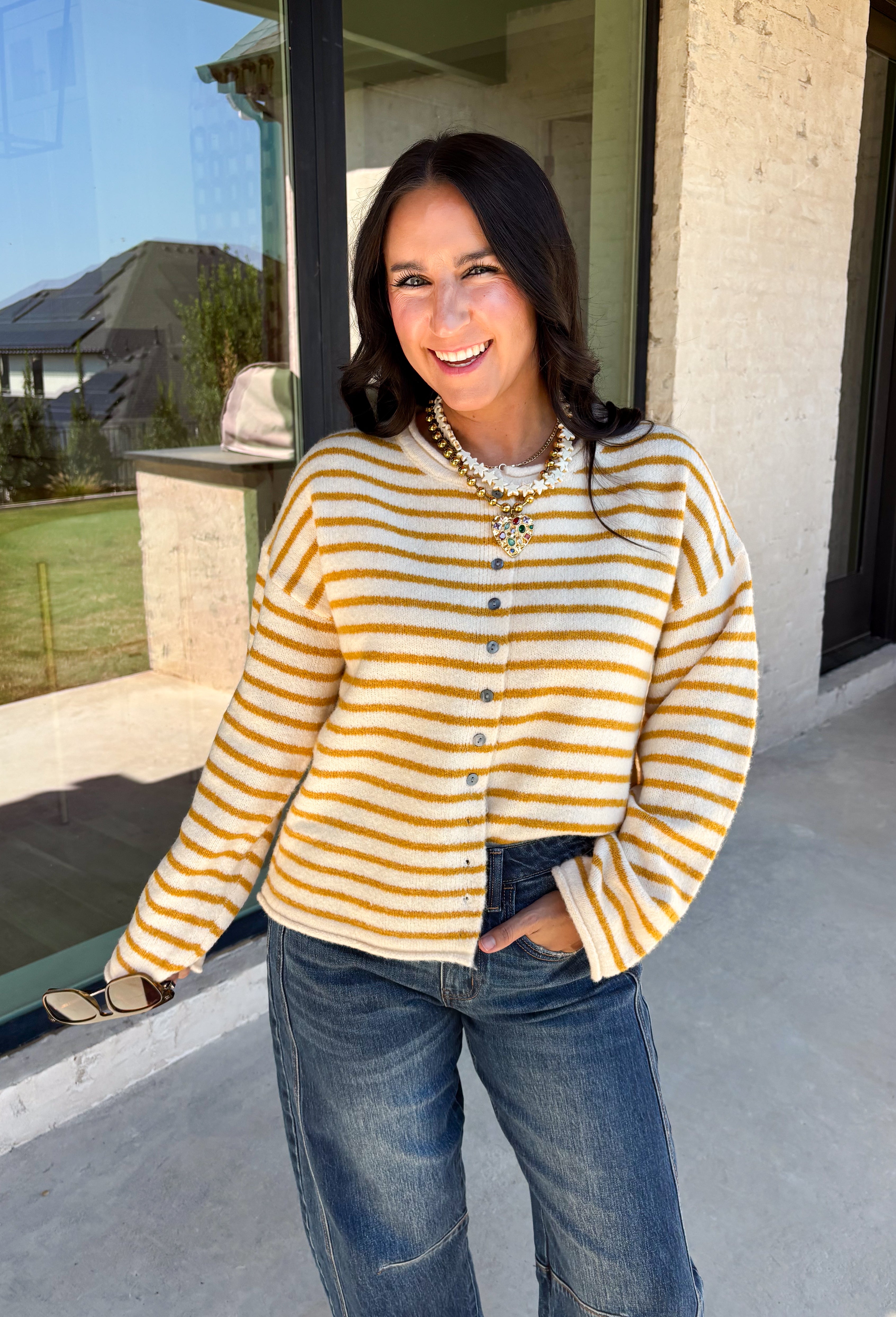 Nothing completes a fall outfit quite like a cozy cardigan. This off white button down cardigan features warm mustard stripes that bring the perfect touch of autumn charm to your wardrobe. The timeless button front makes it easy to wear open or closed, giving you endless styling possibilities throughout the season. Whether you're heading to the office, enjoying a coffee date, or spending the weekend at the pumpkin patch, this soft knit cardigan is one you'll be reaching for again and again.
