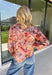 Bring beautiful fall florals into your everyday wardrobe with this effortlessly feminine blouse from Fate. Designed in a soft mauve hue with a floral print in shades of magenta, olive, black, and gray, this timeless top is full of charming details. The button-front design is complemented by a subtle ruffle neckline, while delicate caging detail adds beautiful texture and dimension. 