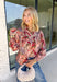 Bring beautiful fall florals into your everyday wardrobe with this effortlessly feminine blouse from Fate. Designed in a soft mauve hue with a floral print in shades of magenta, olive, black, and gray, this timeless top is full of charming details. The button-front design is complemented by a subtle ruffle neckline, while delicate caging detail adds beautiful texture and dimension. 