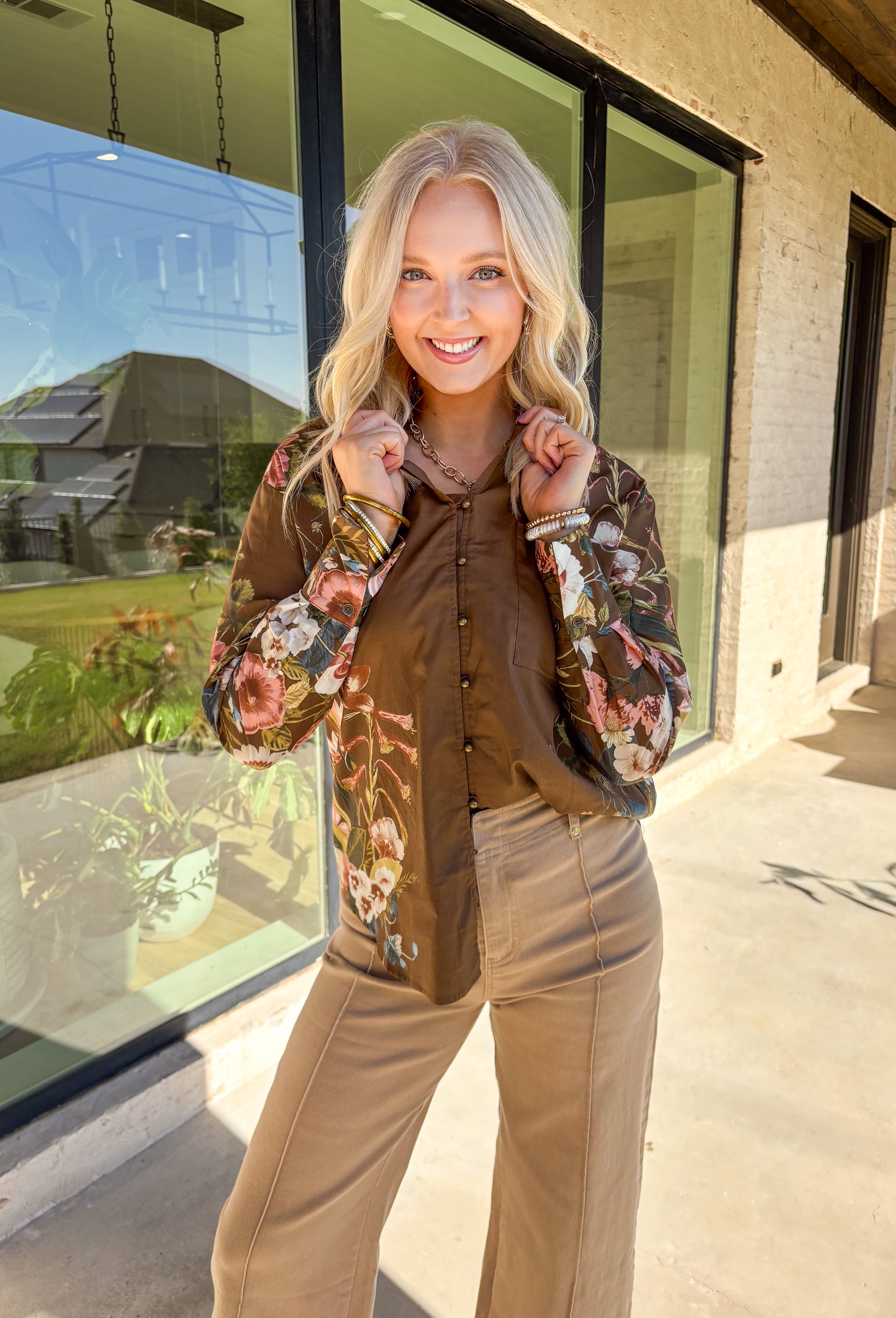 Bring effortless charm to your fall wardrobe with this brown long sleeve top. Designed with floral accent sleeves for a playful pop, it features a ruffle-trimmed v-neckline and button-down front that add a touch of femininity. Made with a soft cotton blend and a hint of stretch, it’s comfortable enough for all-day wear yet stylish enough to dress up or down.