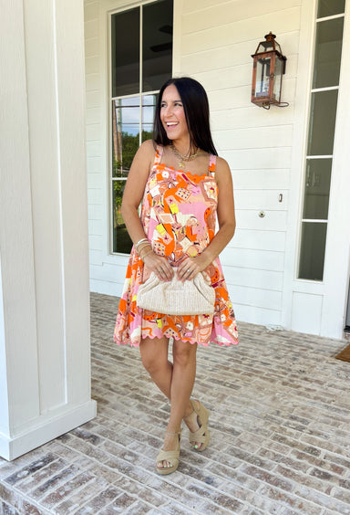 Make an entrance in this bold abstract print dress that was made for sunny days and standout moments. With vibrant shades of orange, pink, tan, black, yellow, and white throughout, this sleeveless beauty feels like wearable art. The orange scallop trim along the neckline and pink scallop trim at the hem add the sweetest contrast, giving it that extra pop of personality. Lightweight and fully lined for easy wear.
