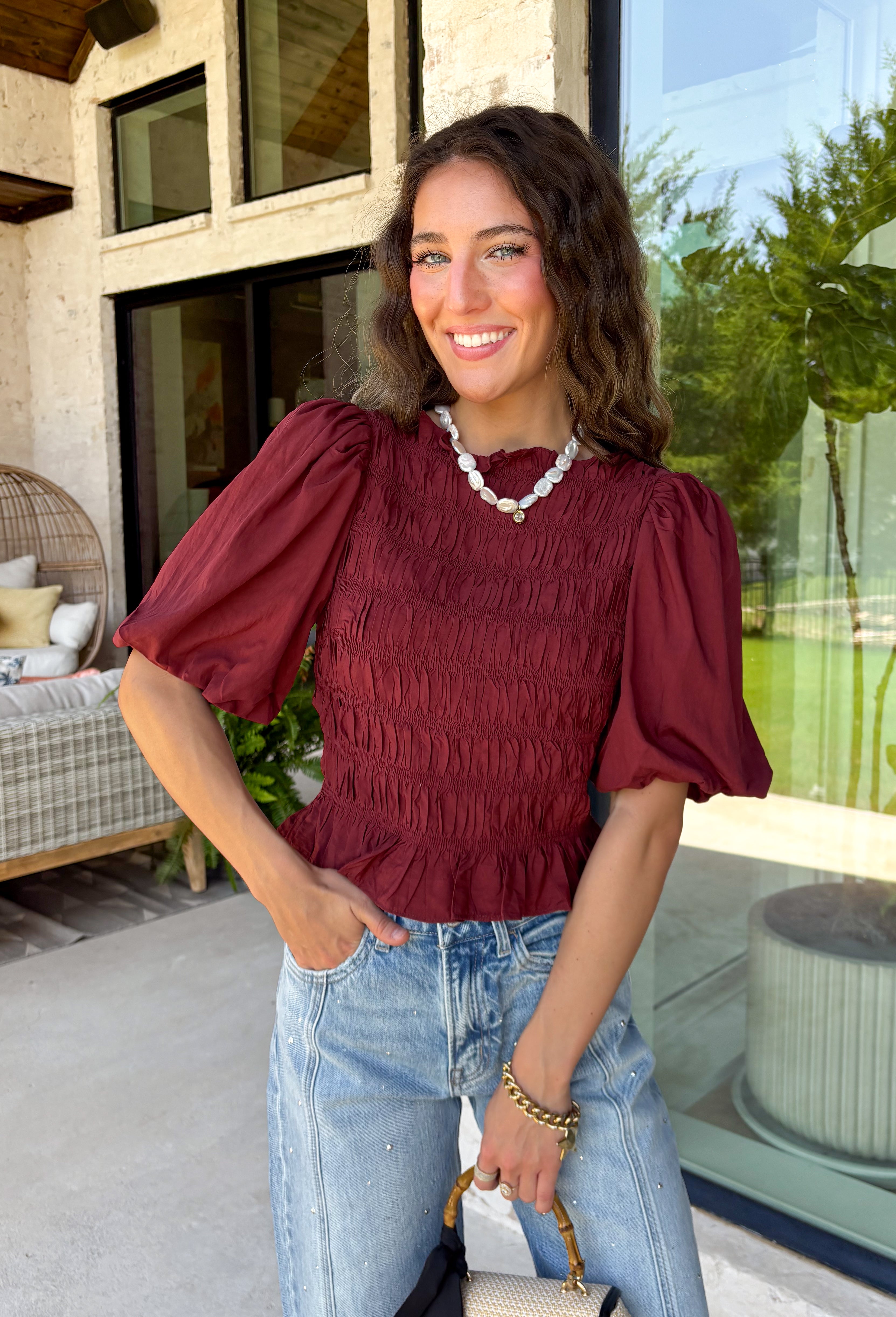 Rich autumn color and feminine details come together beautifully in this brick peplum top. Designed with a flattering smocked bodice, this top offers a comfortable fit while creating a timeless silhouette you'll love. The delicate ruffle neckline and ruffle hem add just the right amount of charm, while the puff sleeves complete the look with a classic fall feel. 