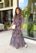 Turn heads at your next special event in this stunning floral maxi dress from Entro. Featuring a rich brown backdrop with a beautiful blue floral print, this elegant dress is designed to make every occasion feel a little more special. The self-tie detail at the back neckline adds a graceful finishing touch, while the flowing maxi silhouette creates effortless movement with every step. 