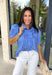This blue short sleeve top by Entro is giving the perfect mix of classic and cute for spring. Featuring a crisp white stripe print with delicate floral embroidery in green and pink, it’s one of those tops that feels extra special without trying too hard. The button-front design and subtle ruffle detail add a sweet finishing touch, making it easy to dress up with white denim or keep casual with your favorite everyday jeans.